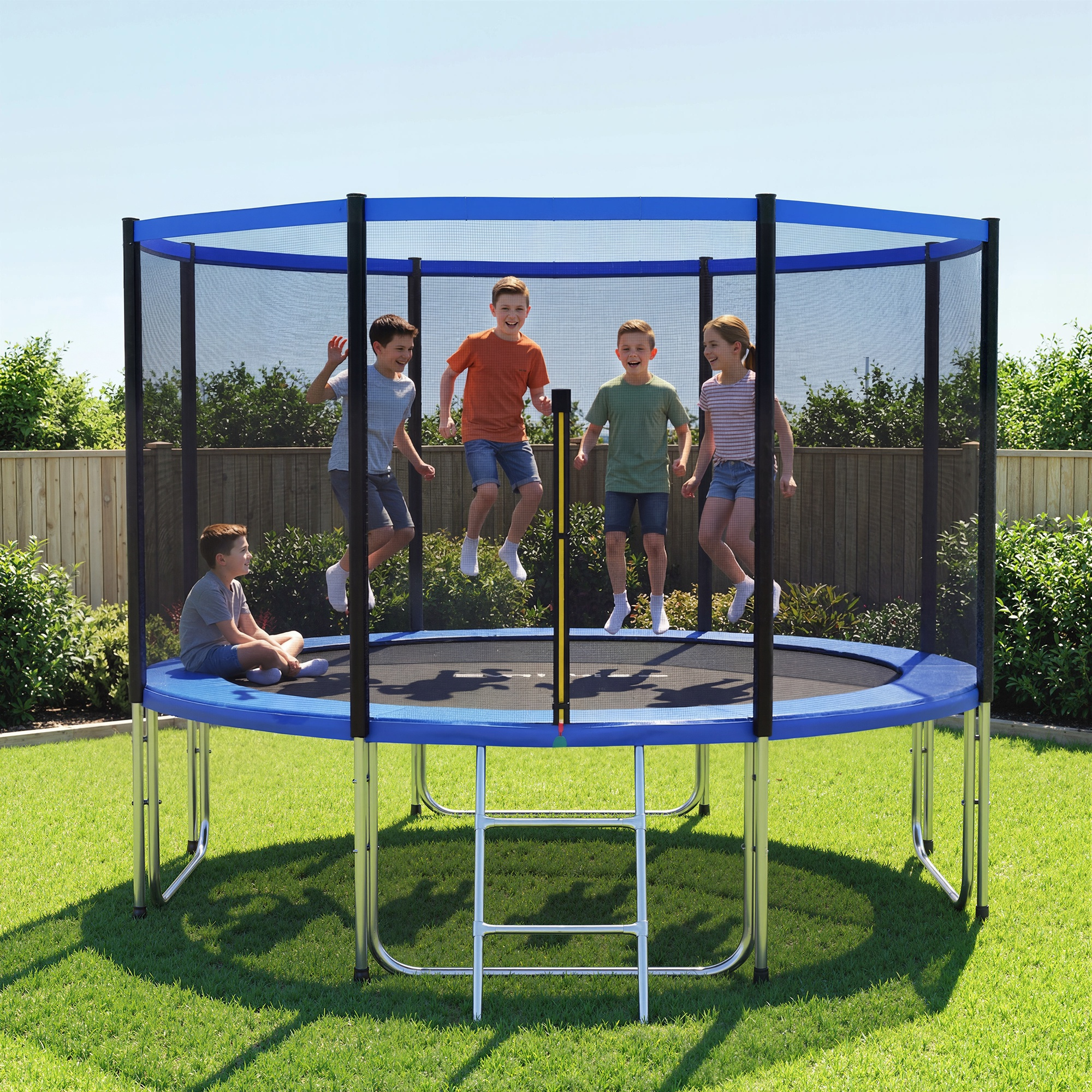 Cinco niños en un trampolín azul en un patio verde, cuatro saltando y uno sentado. Hay una valla de madera al fondo.