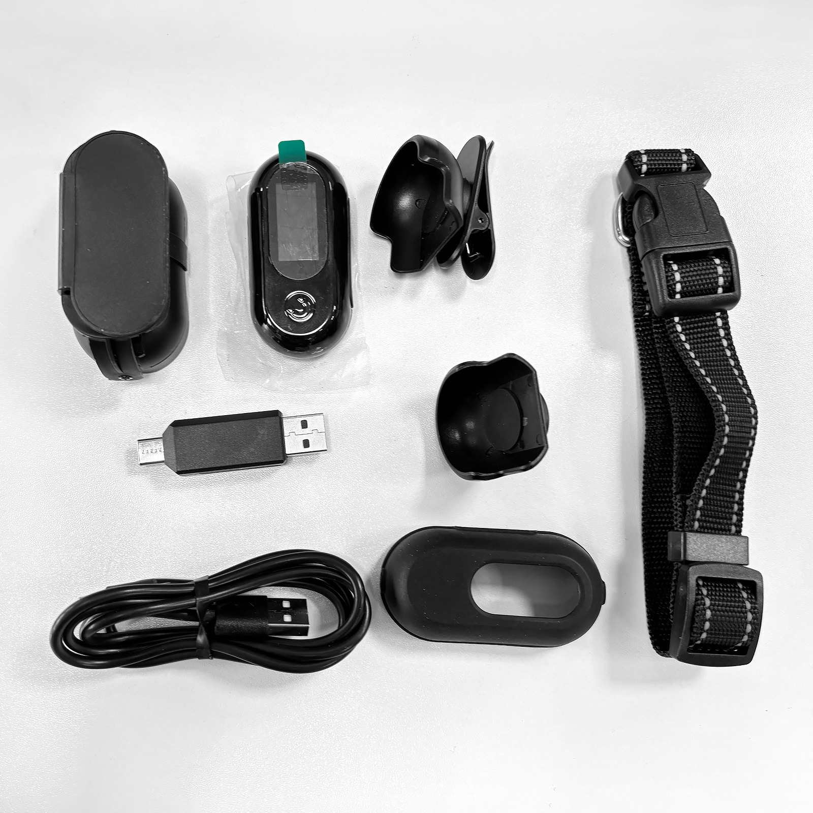 Black and white flat lay of pet tracker accessories including a collar, chargers, and clips.