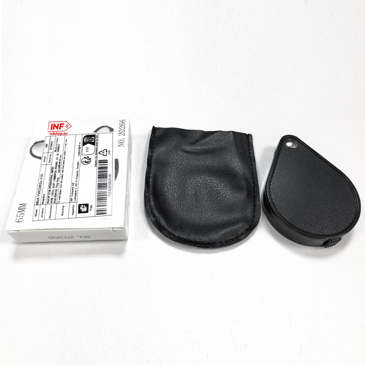 Eine Lupe mit schwarzem Griff, eine schwarze Tasche und eine weiße Verpackung liegen nebeneinander.