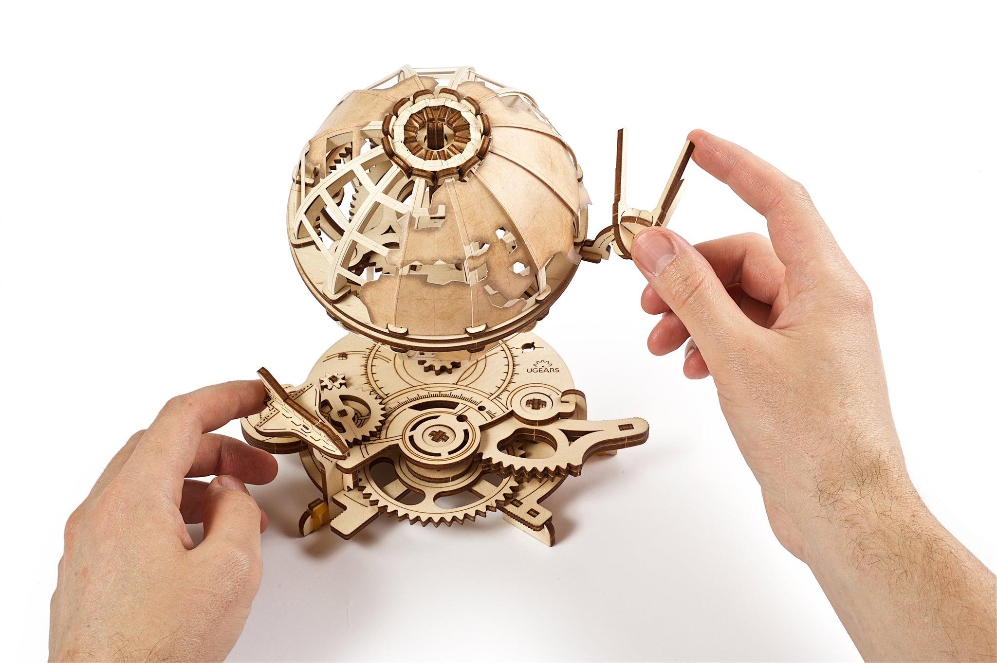 Ręce składają drewniany mechaniczny model globu z zębatkami.