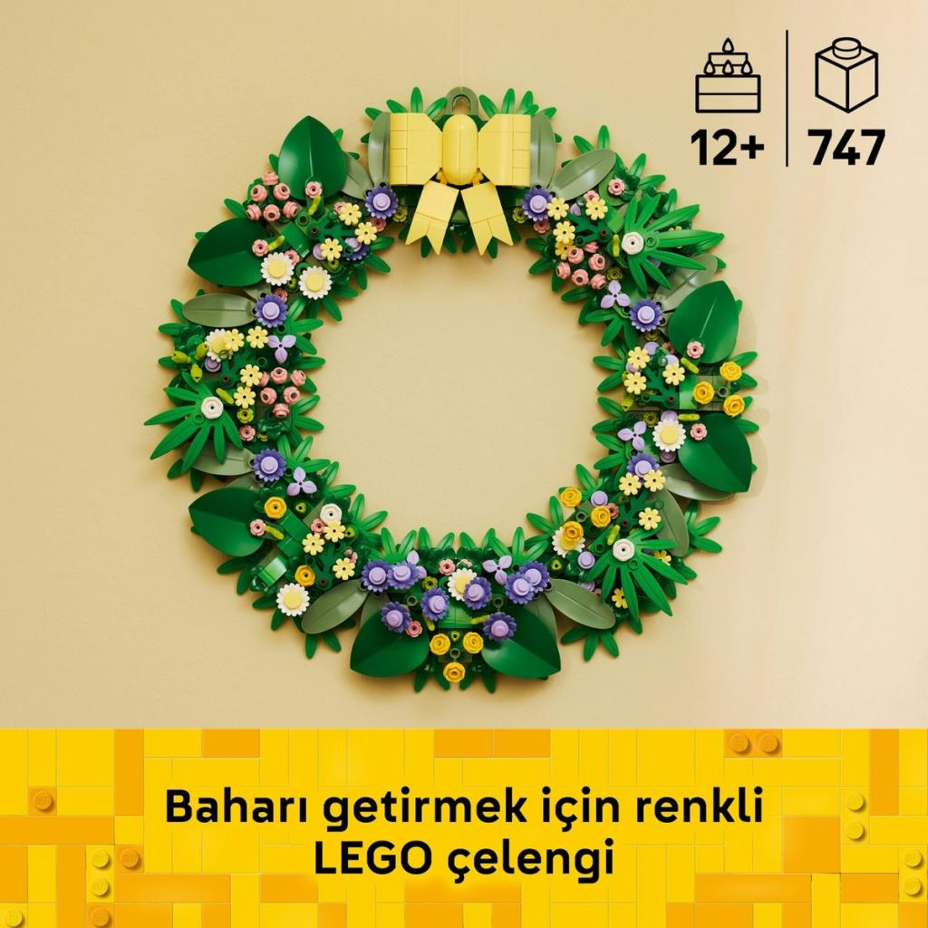 Yeşil yapraklı, renkli çiçekli ve sarı fiyonklu bir LEGO çelengi.