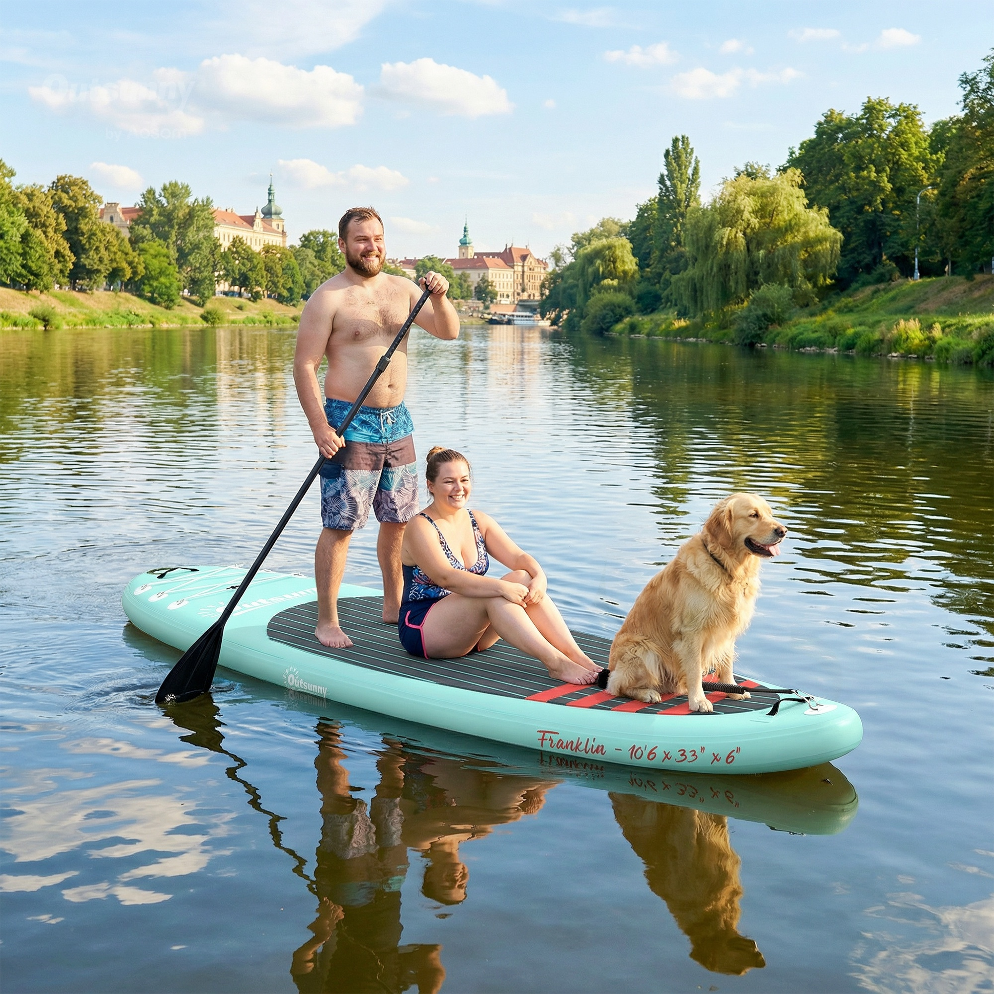 Hombre, mujer y perro en tabla de paddle surf en río con ciudad al fondo.