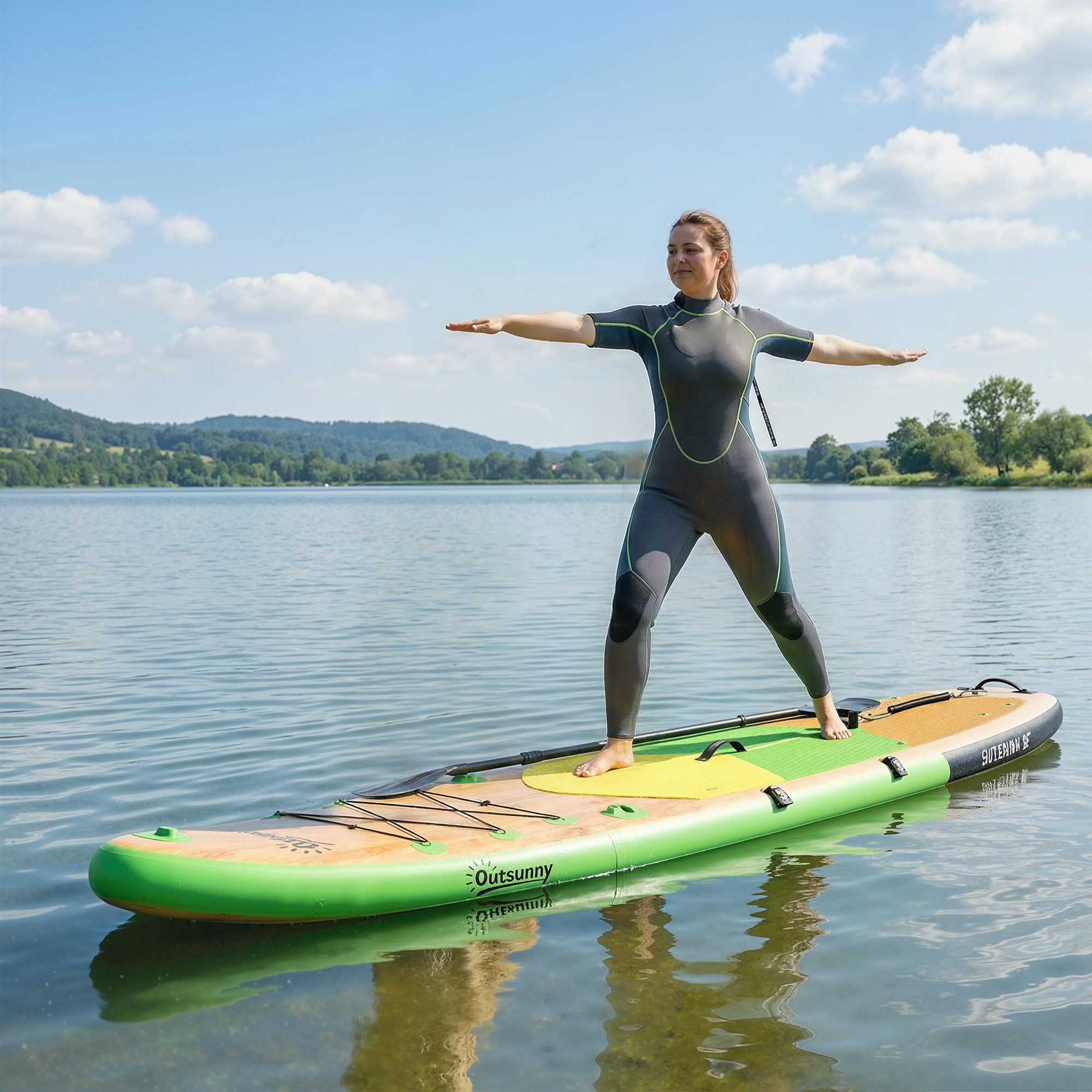 Una mujer con traje de neopreno practica yoga en una tabla de paddle surf en un lago.