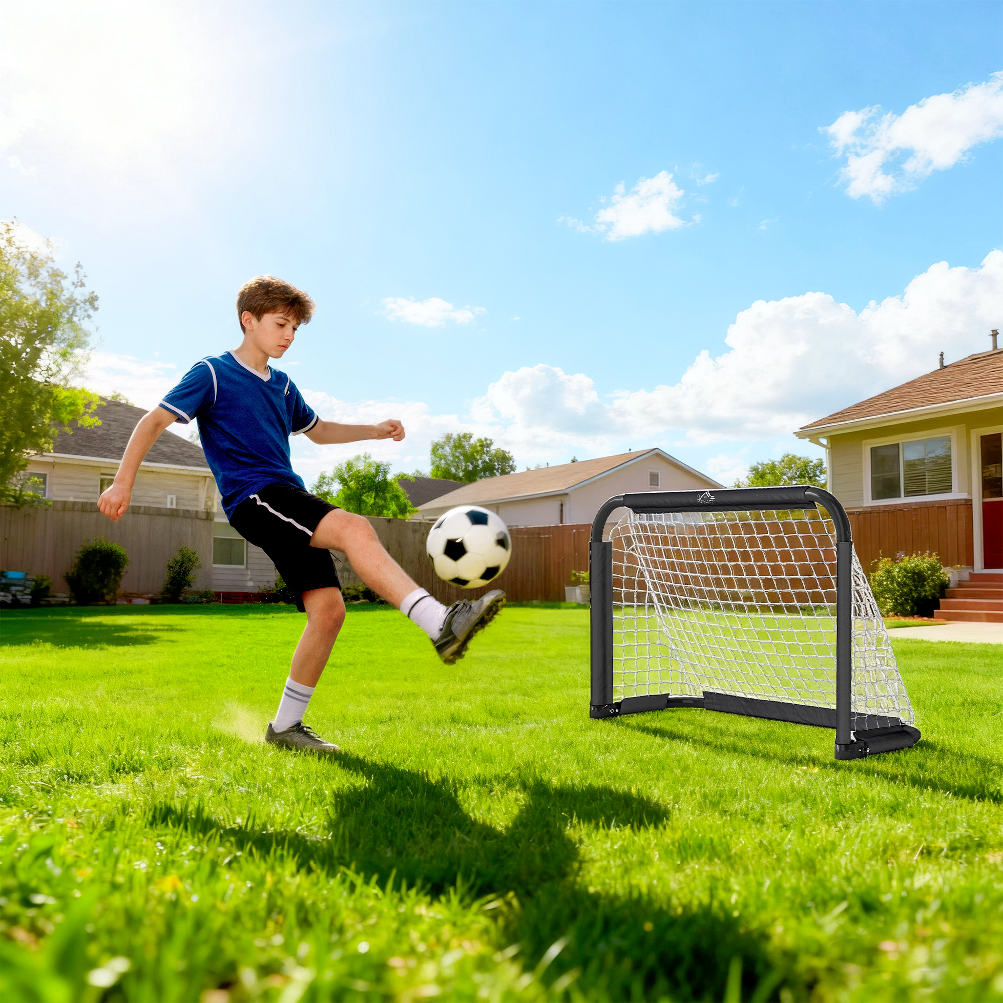 Un niño con camiseta azul patea un balón de fútbol que vuela por el aire.