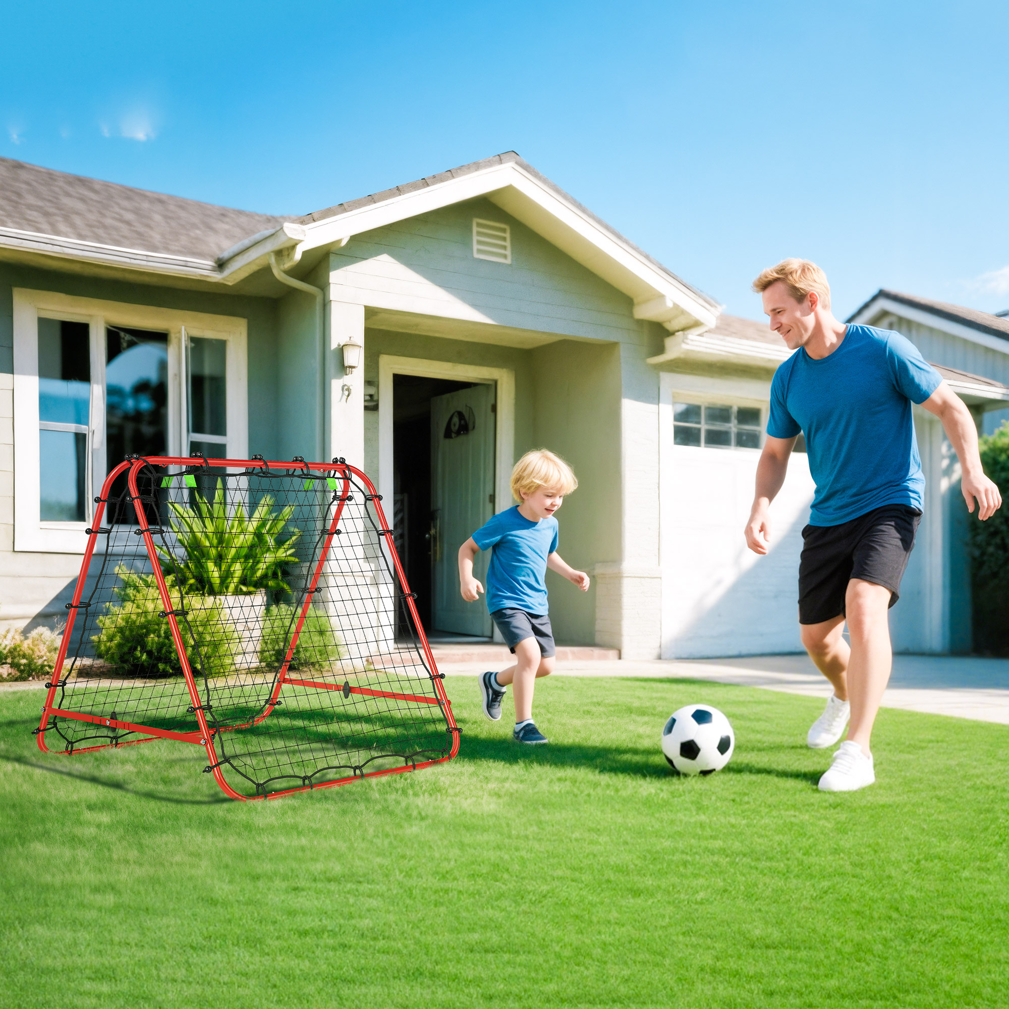 Padre e hijo juegan al fútbol en el césped frente a una casa con una portería roja.