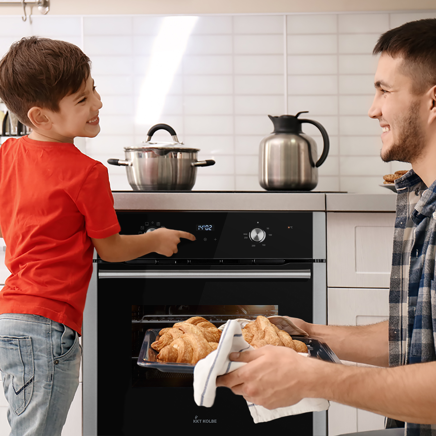 Vater und Sohn backen Croissants in einer Küche. Junge bedient Backofen.