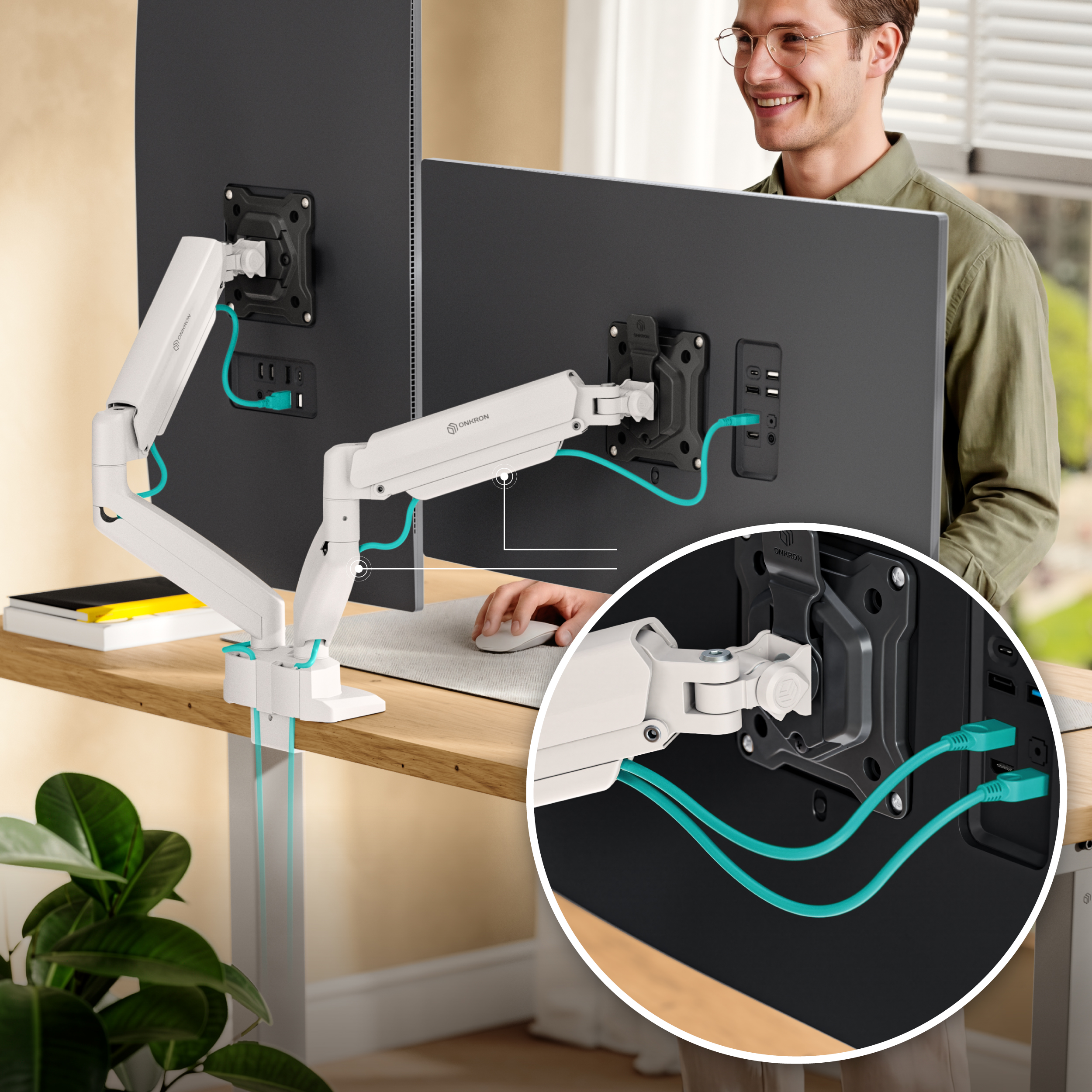 Ein Mann lächelt, während er an einem Schreibtisch mit zwei Monitoren sitzt, die an einer weißen Halterung befestigt sind.