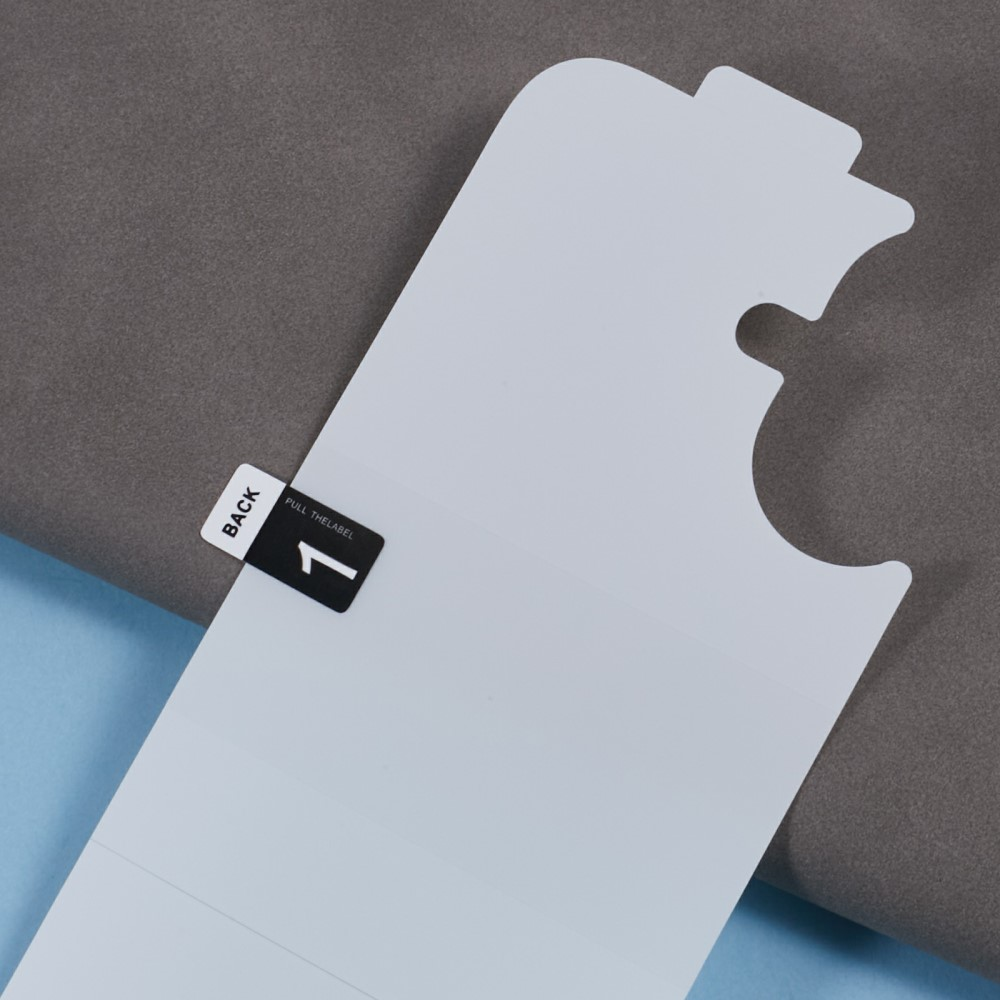 Un film protecteur blanc avec une languette noire indiquant 'BACK 1 PULL THE LABEL'.