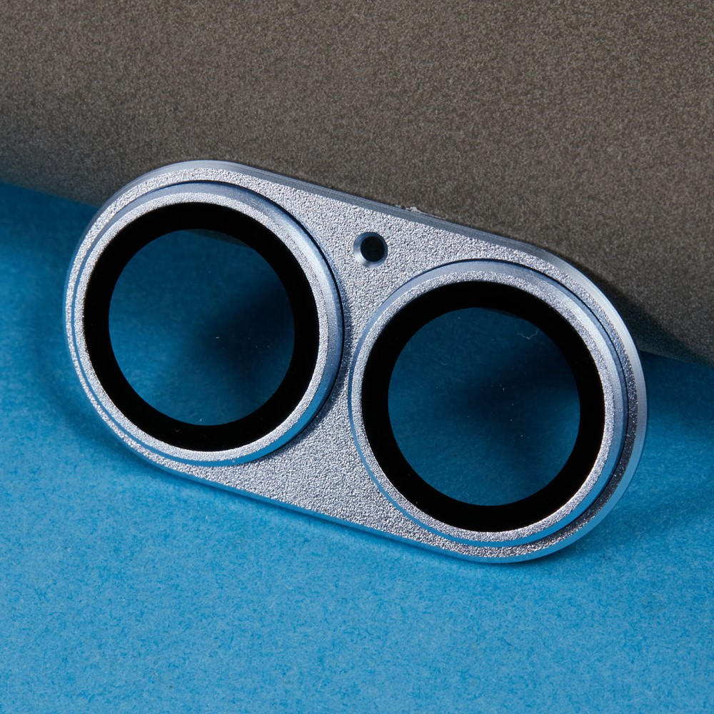 Ensemble de lentille de caméra double argentée avec bords noirs sur surface bleue.