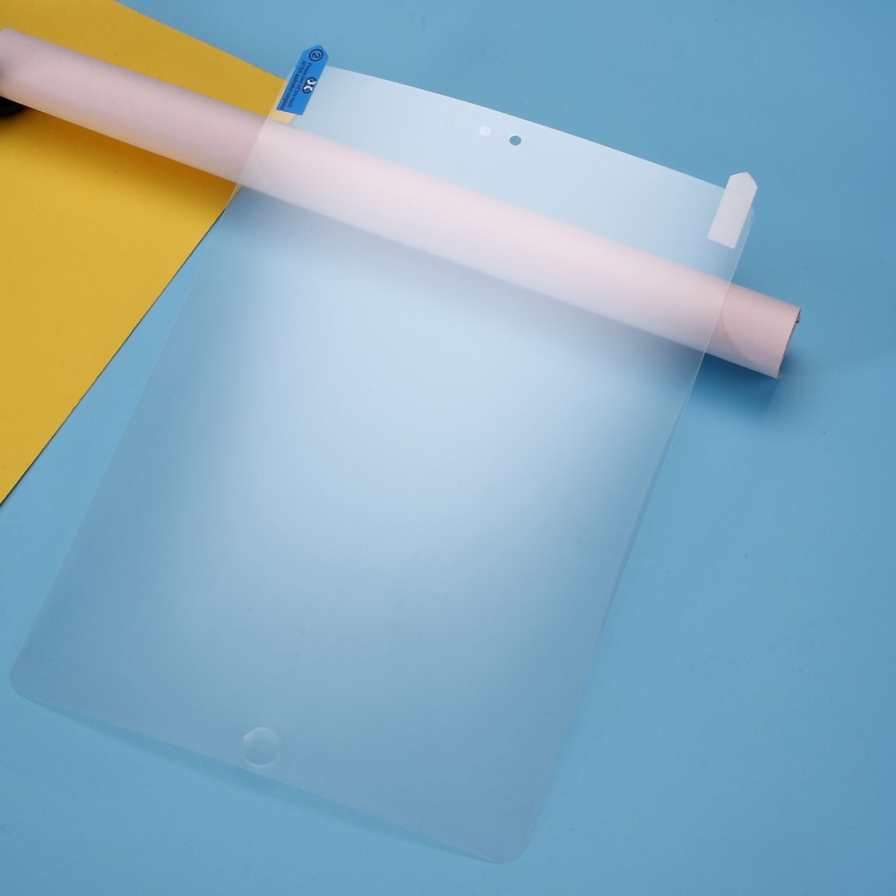 Un protecteur d'écran mat pour tablette repose sur une surface bleue et jaune.