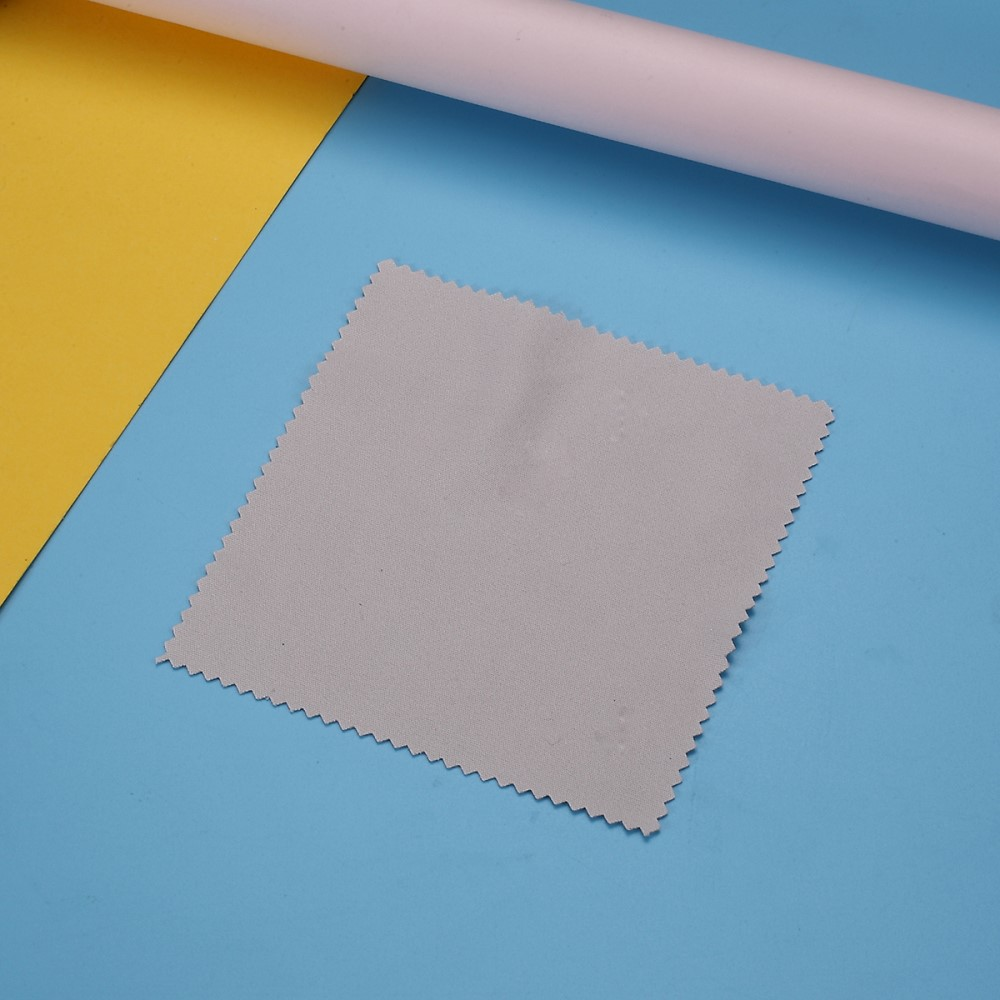 Chiffon microfibre gris à bords dentelés sur fond bleu et jaune.