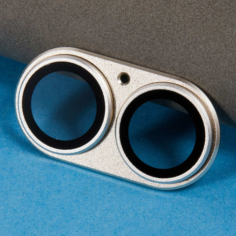 Un cadre argenté double caméra avec des lentilles noires sur fond bleu et gris.