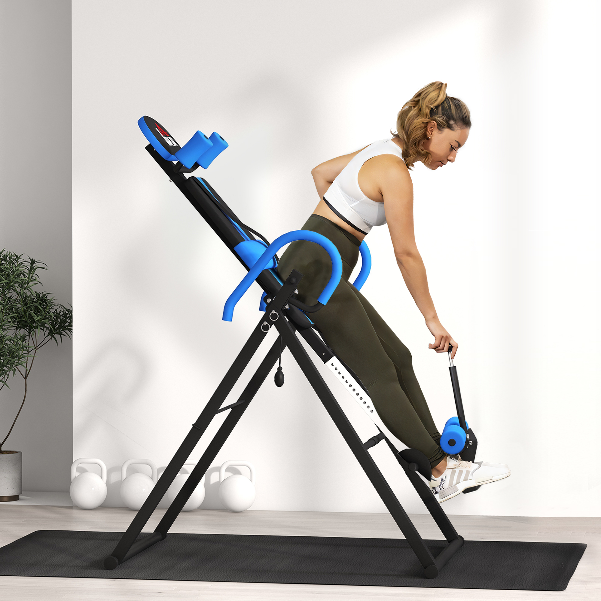Una mujer en una máquina de inversión en un gimnasio. Hay pesas rusas en el suelo.