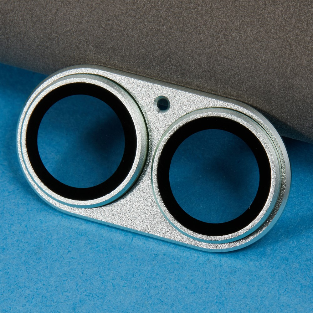 Objectif double argenté avec anneaux noirs sur surface bleue.