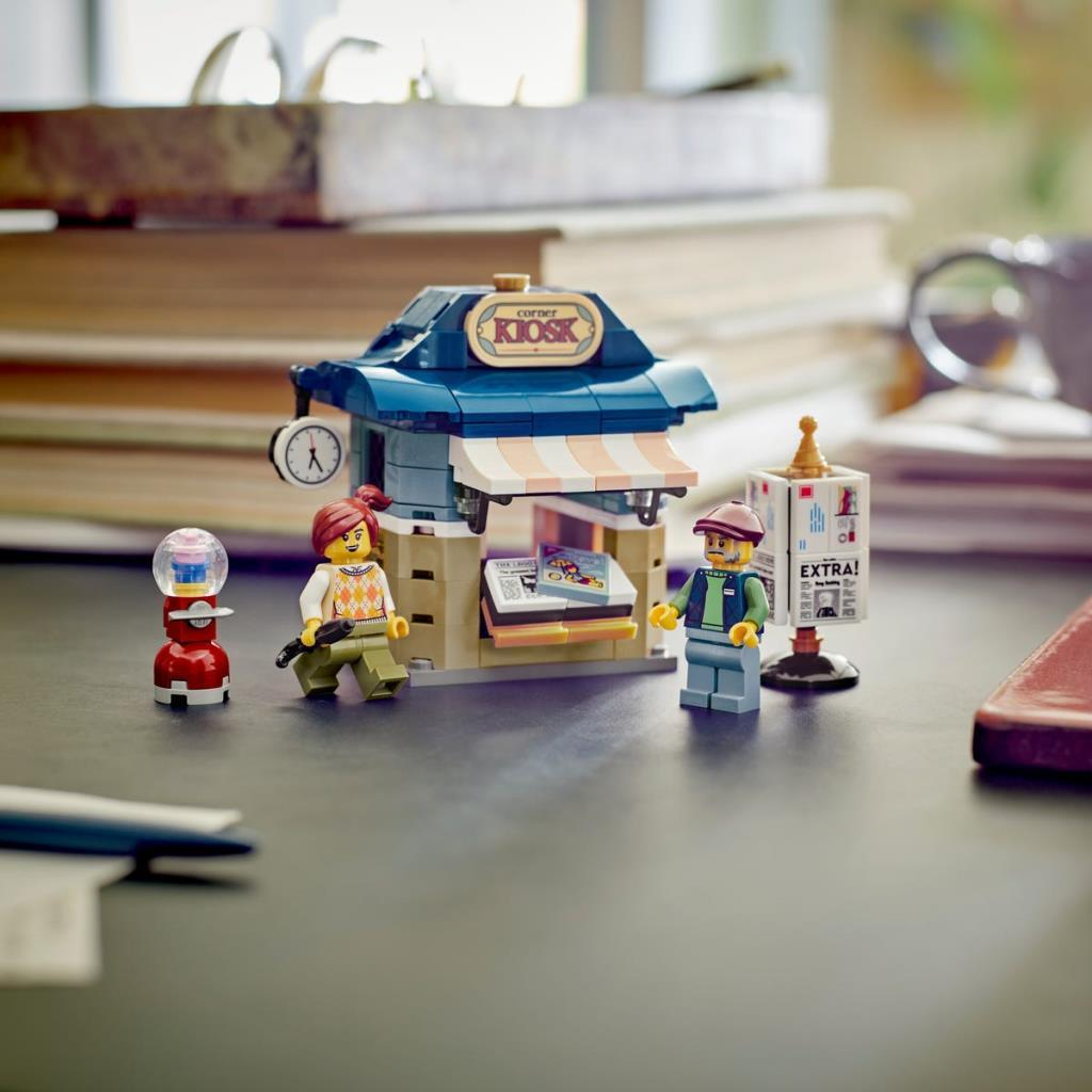 Chiosco Lego con due minifigure, una macchinetta per gomme e un edicola su un tavolo.