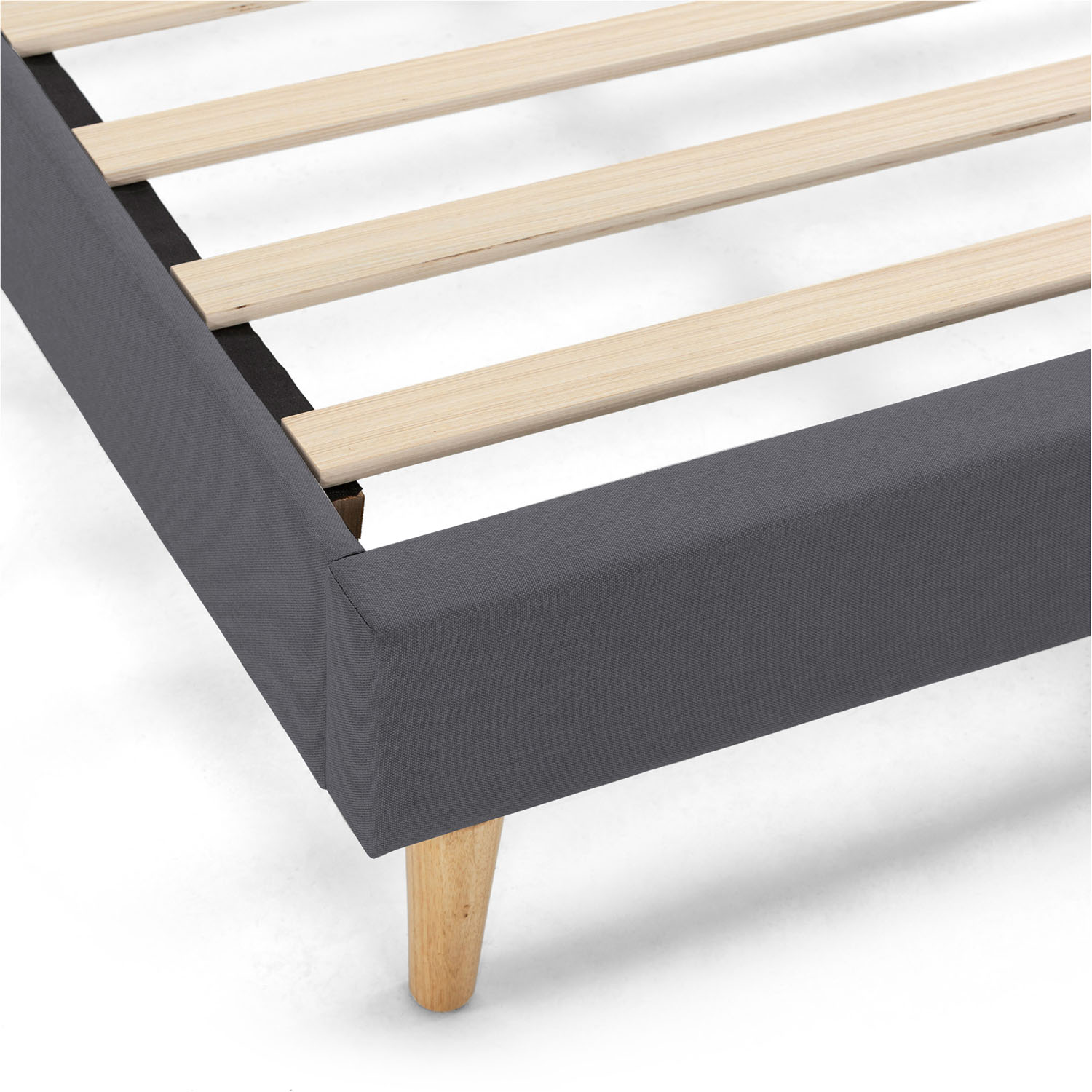 Primer plano de un somier tapizado gris con listones de madera y patas anguladas.