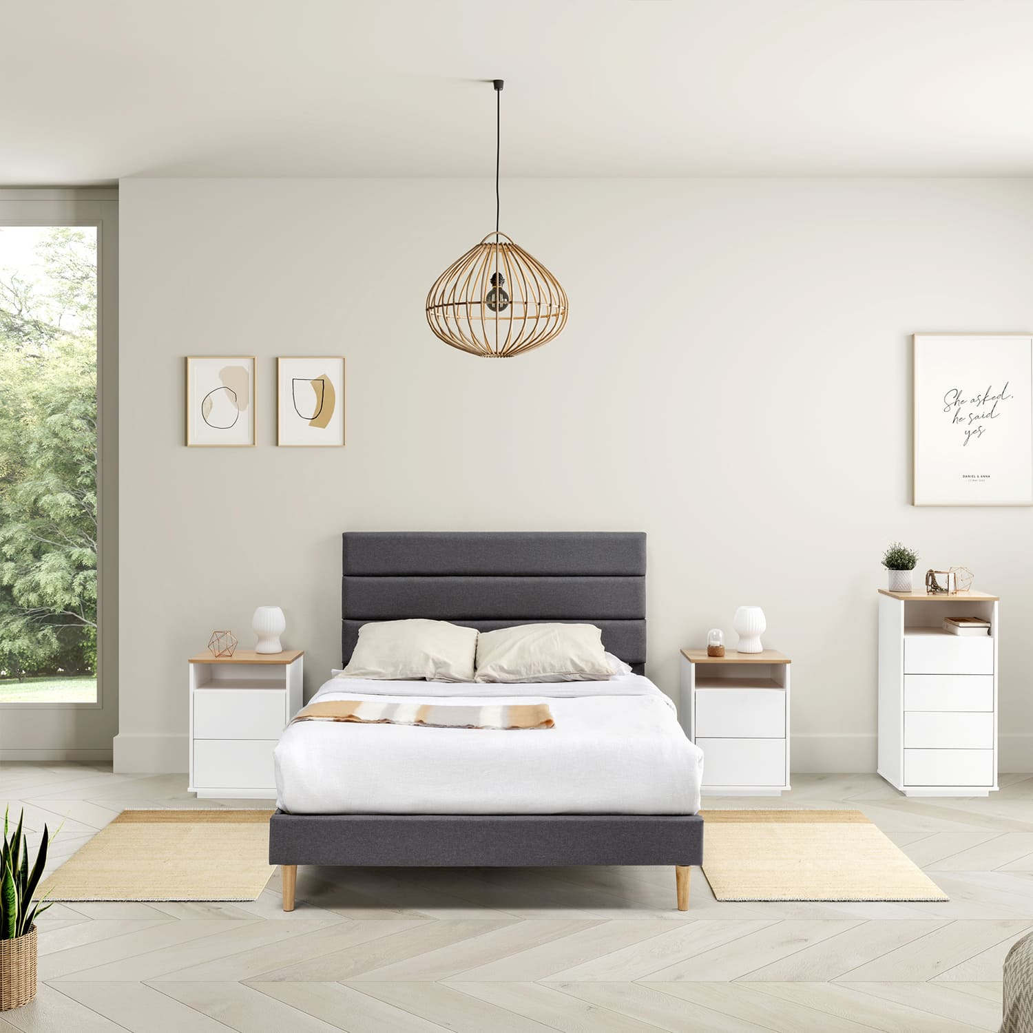 Un dormitorio con cama oscura, dos mesitas de noche blancas y una ventana.