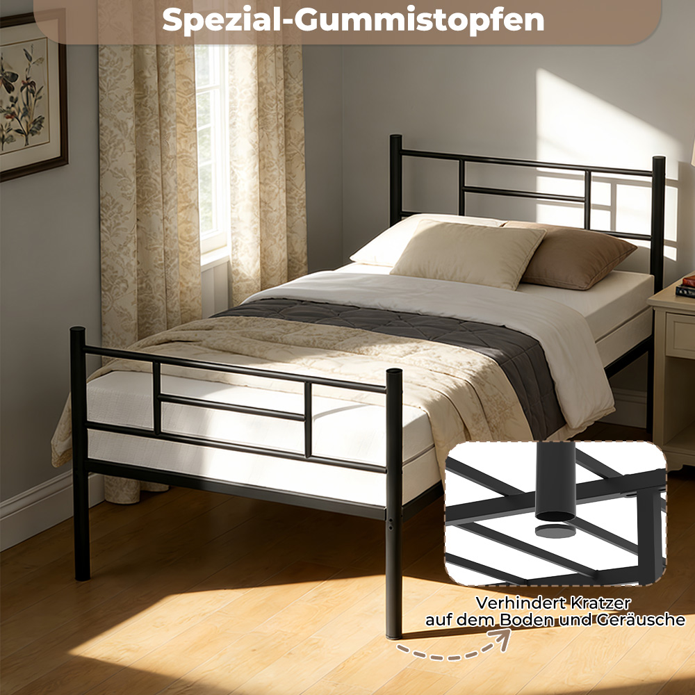 Schwarzes Metallbett mit weißer Matratze, Kissen und Decken. Am Fußende ist ein Gummistopfen zu sehen.