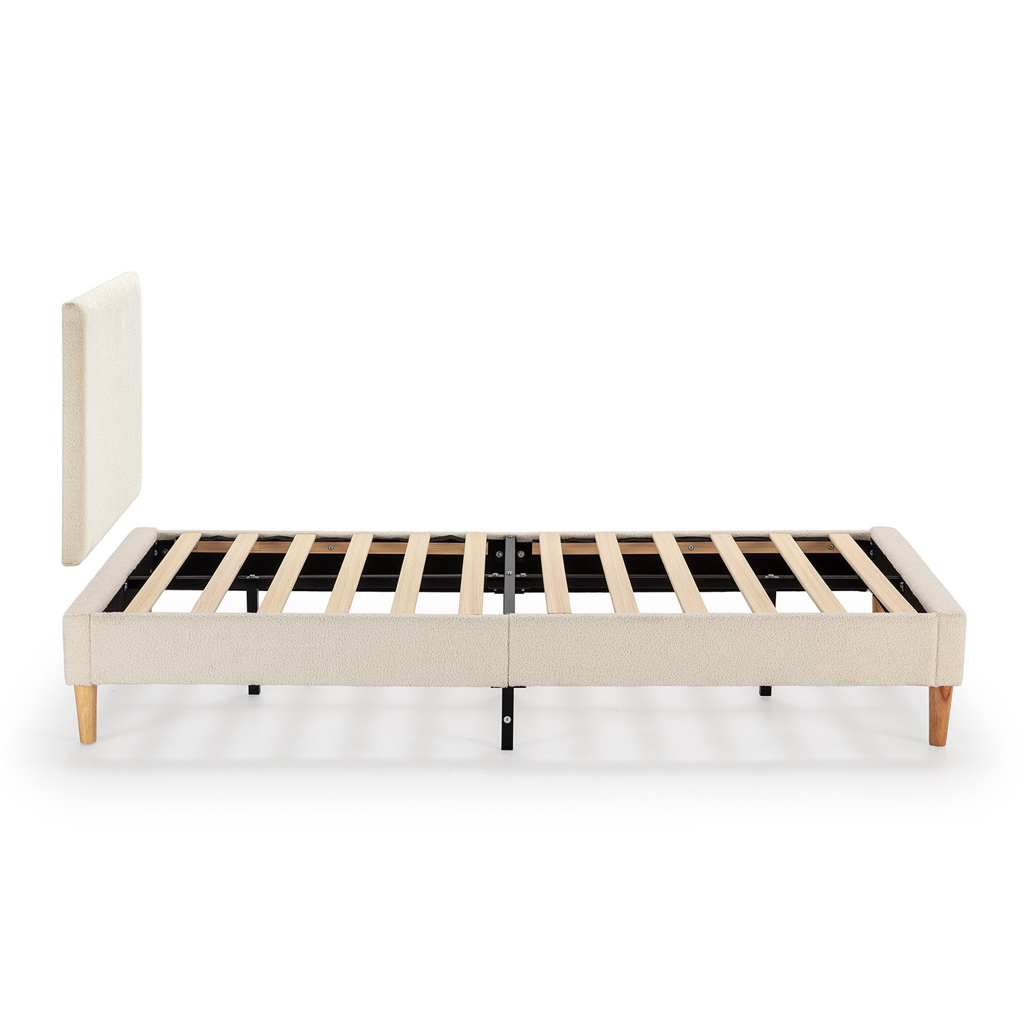 Estructura de cama tapizada crema con listones de madera y cabecero desmontado.