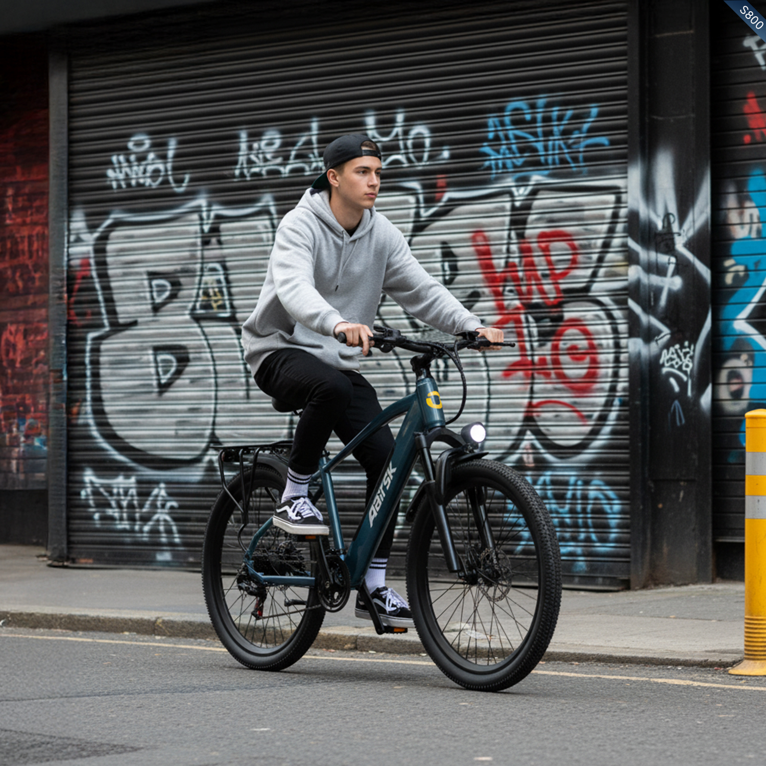 Ein junger Mann fährt Fahrrad vor einer Graffiti-Wand.