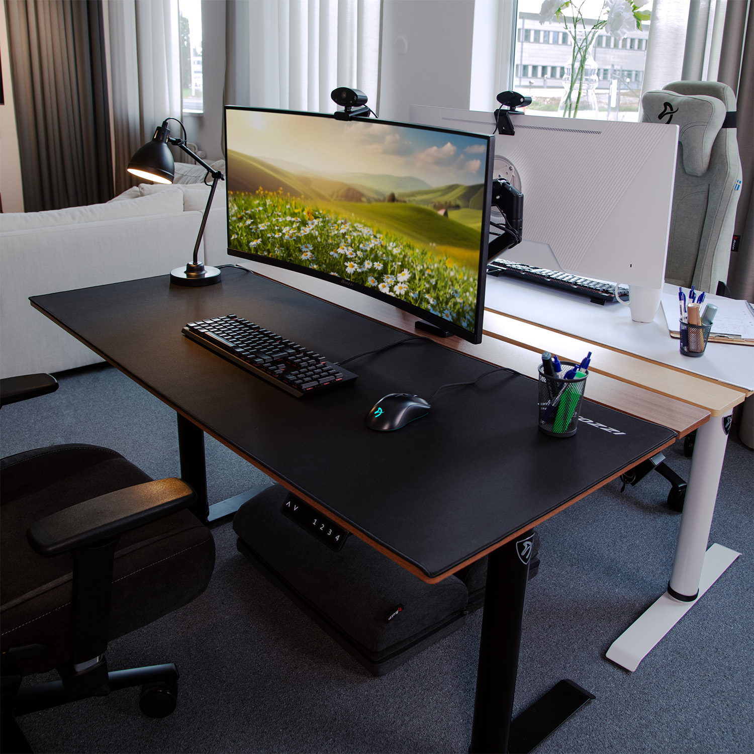 Una postazione da scrivania moderna con doppio monitor, tastiera, mouse e lampada.