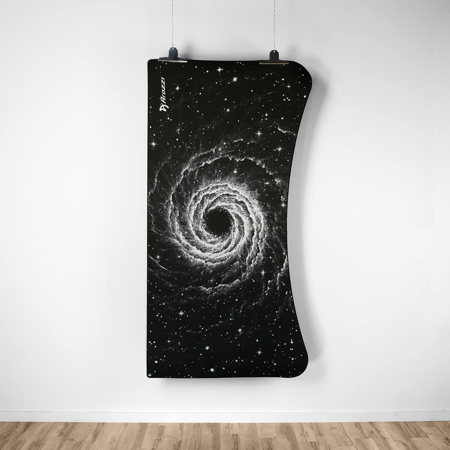 Un telo nero con disegno di galassia, appeso a una parete bianca.