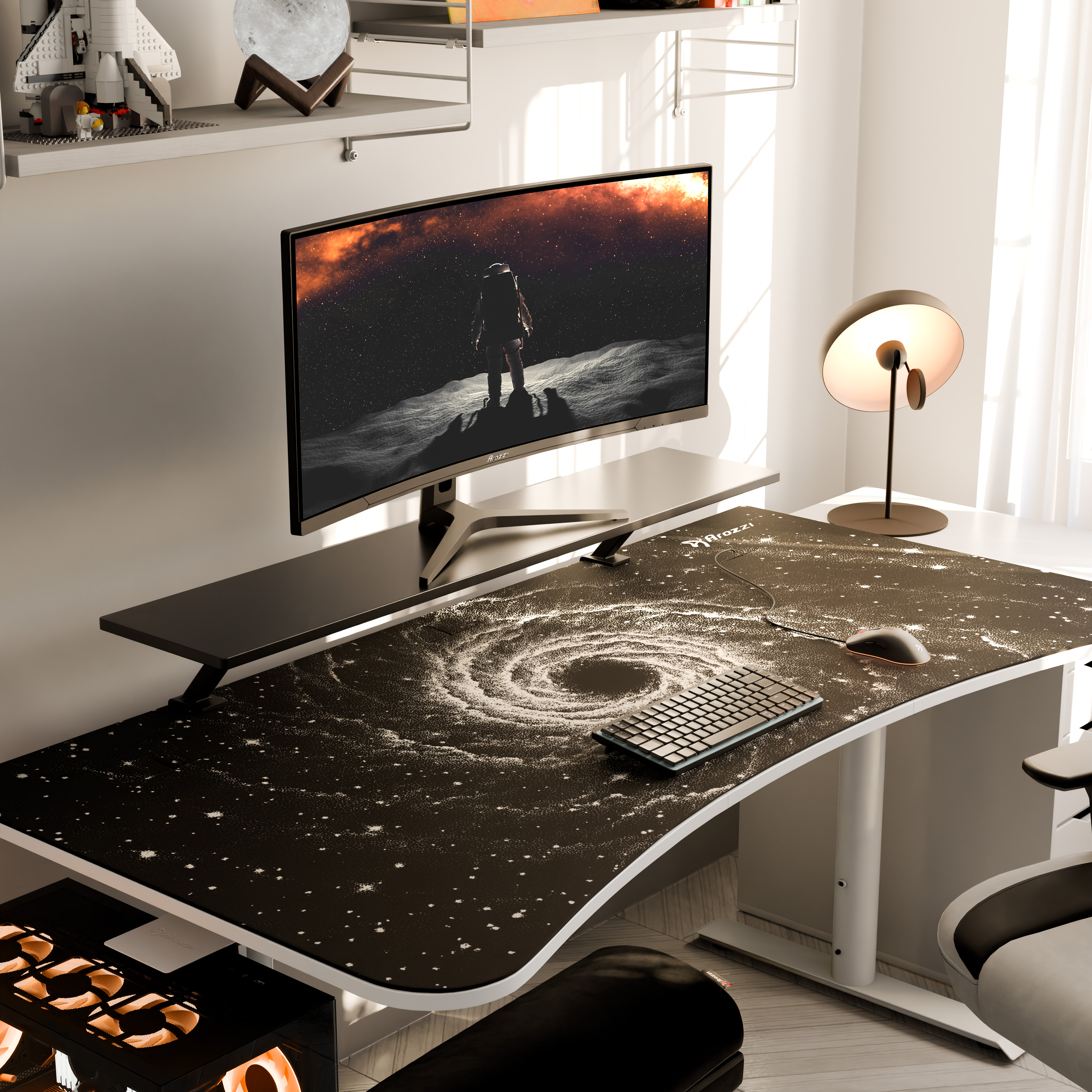 Scrivania gaming con mousepad, tastiera e monitor a tema spaziale.