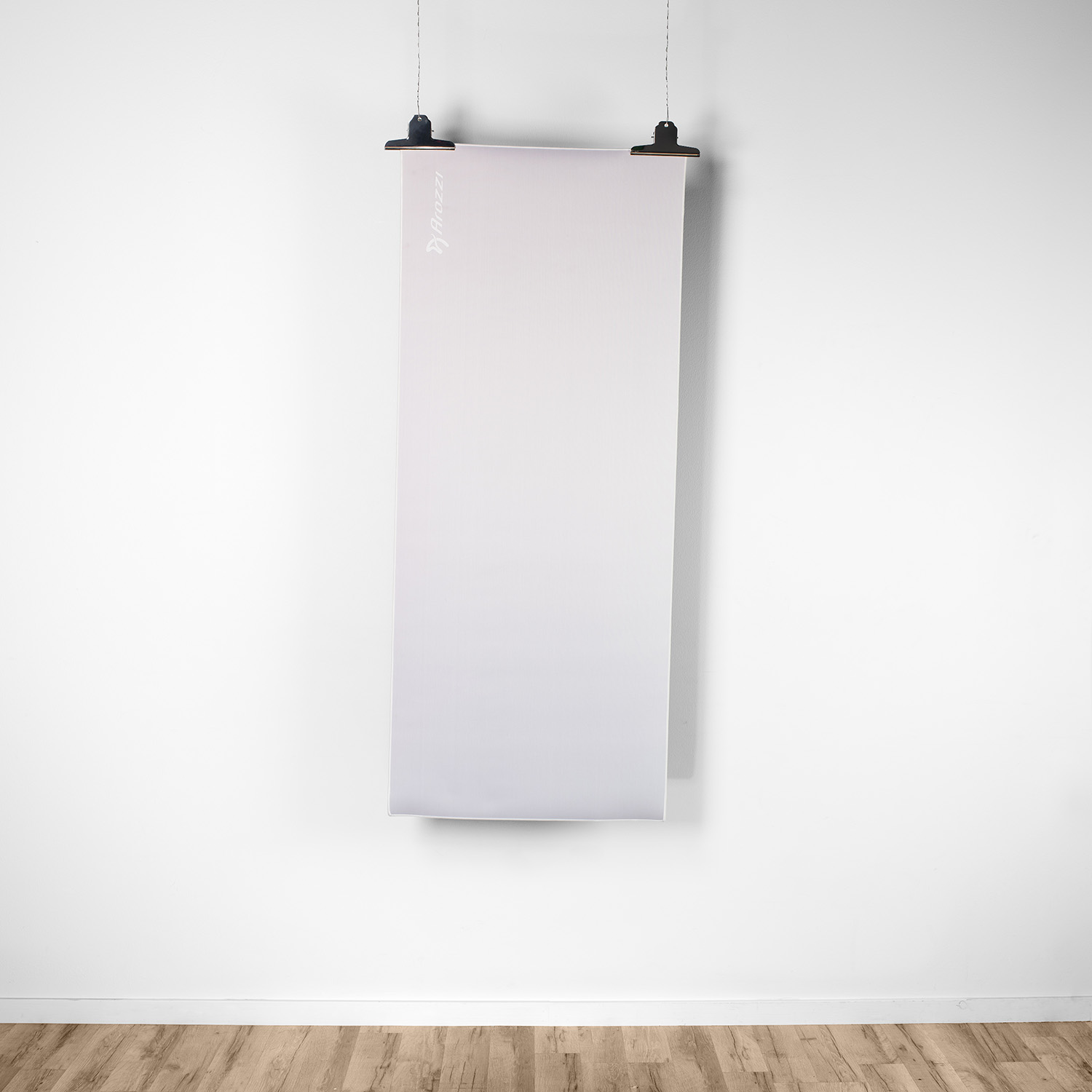 Un banner bianco con logo appeso a clip su muro bianco sopra pavimento in legno.