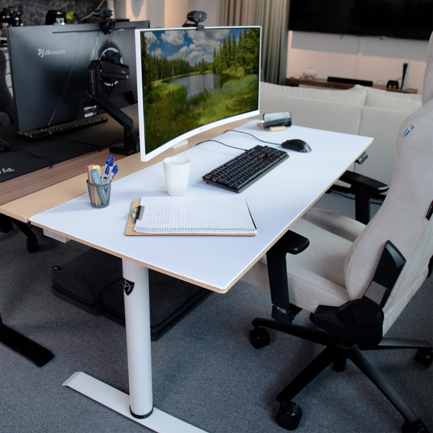 Una scrivania regolabile in altezza bianca con due monitor, tastiera, mouse, tazza e penne.