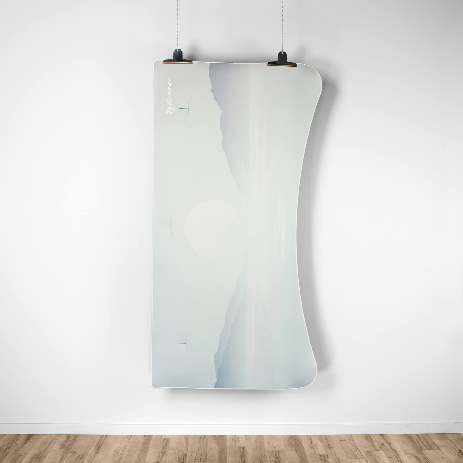 Un poster bianco con paesaggio montano e sole, appeso a un muro.