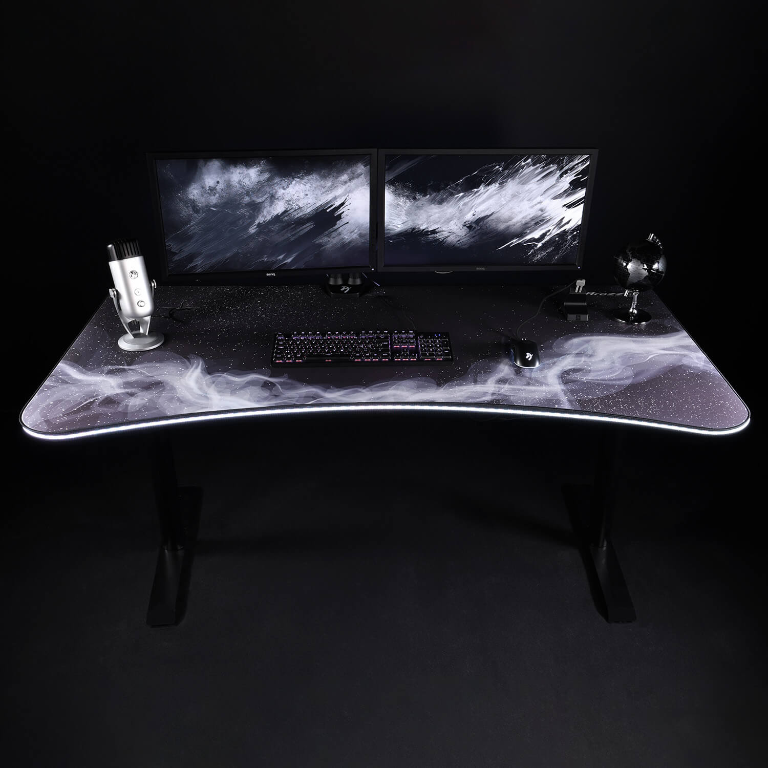 Una scrivania da gaming con due monitor, tastiera, mouse e microfono.
