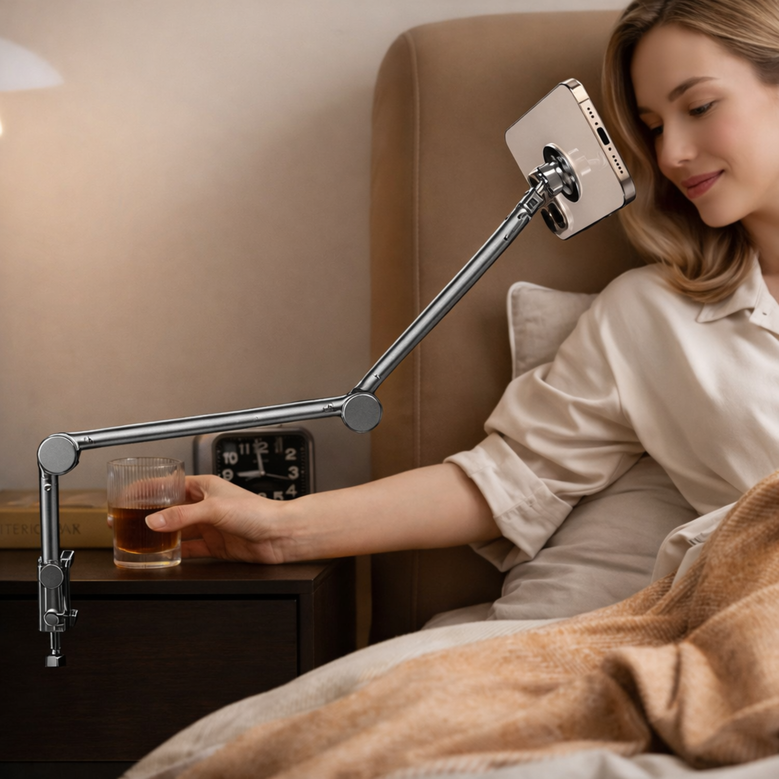 Eine Frau im Bett mit einem Handyhalter, daneben ein Glas und ein Nachttisch.