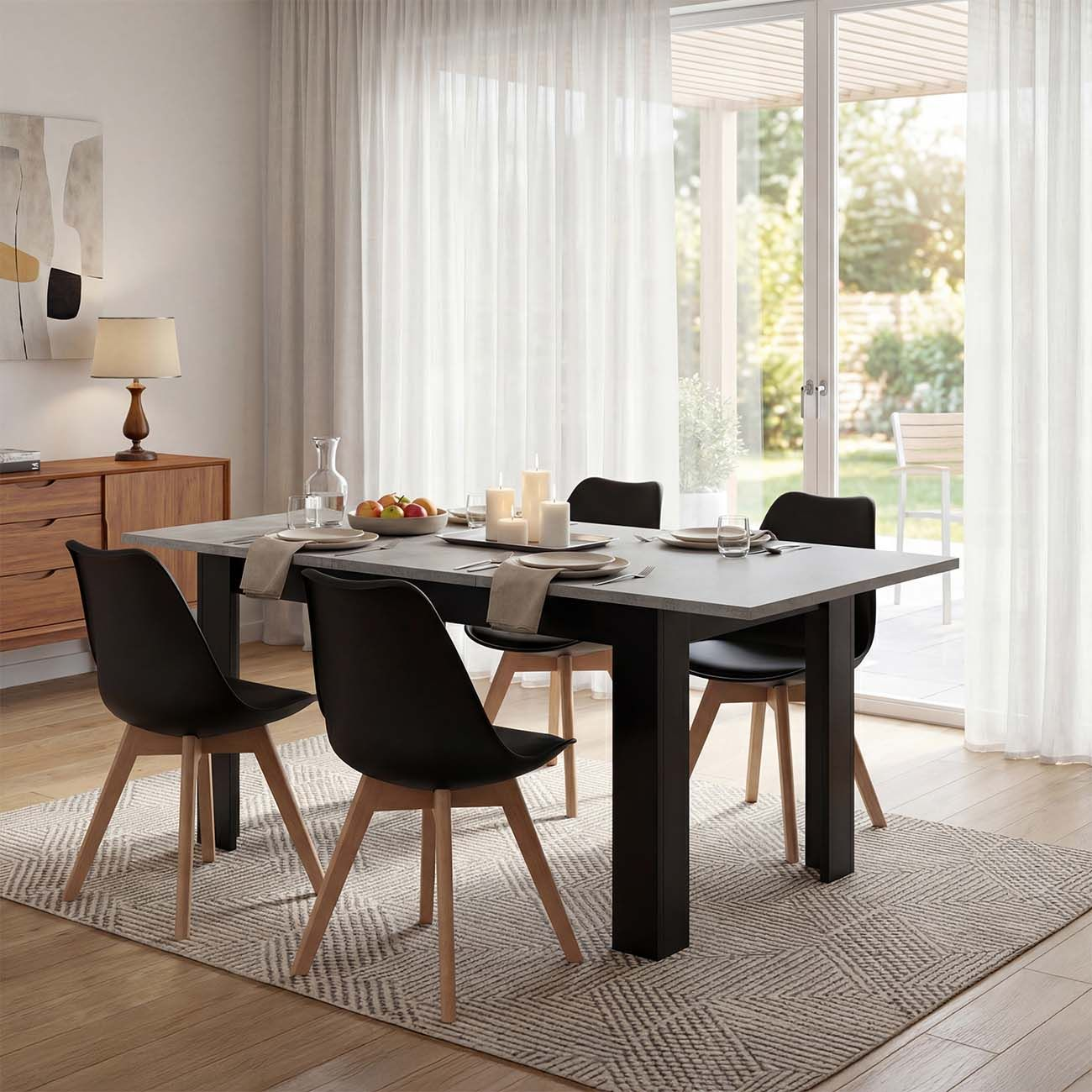 Moderna zona de comedor con mesa gris, sillas negras y suelo de madera.