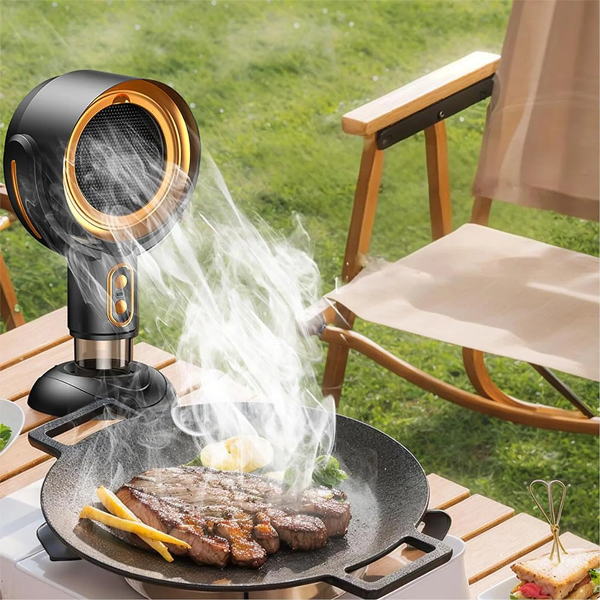 Ein schwarzer Ventilator bläst Dampf auf einen brutzelnden Steak in einer Pfanne im Freien.
