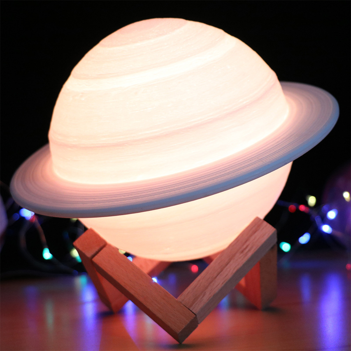 Eine leuchtende Lampe in Planetenform mit Ringen, auf einem Holzständer, vor einem dunklen Hintergrund mit Lichtern.