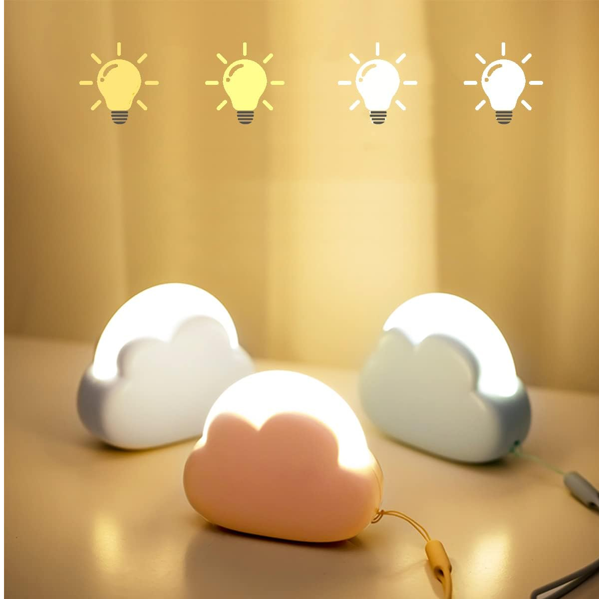 Drei Wolkenlampen auf einem Tisch: eine rosafarbene, eine weiße und eine hellblaue.