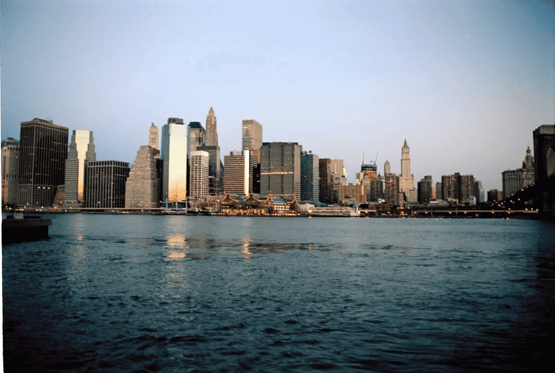El horizonte de Manhattan al anochecer con agua en primer plano.
