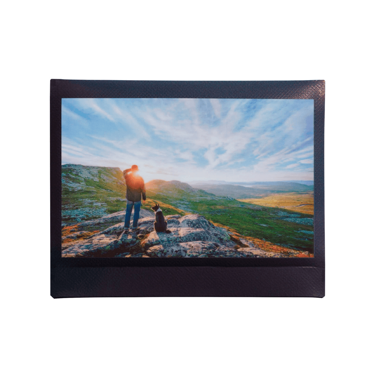 Mann und Hund auf einem Felsen mit Blick auf eine bergige Landschaft bei Sonnenuntergang.