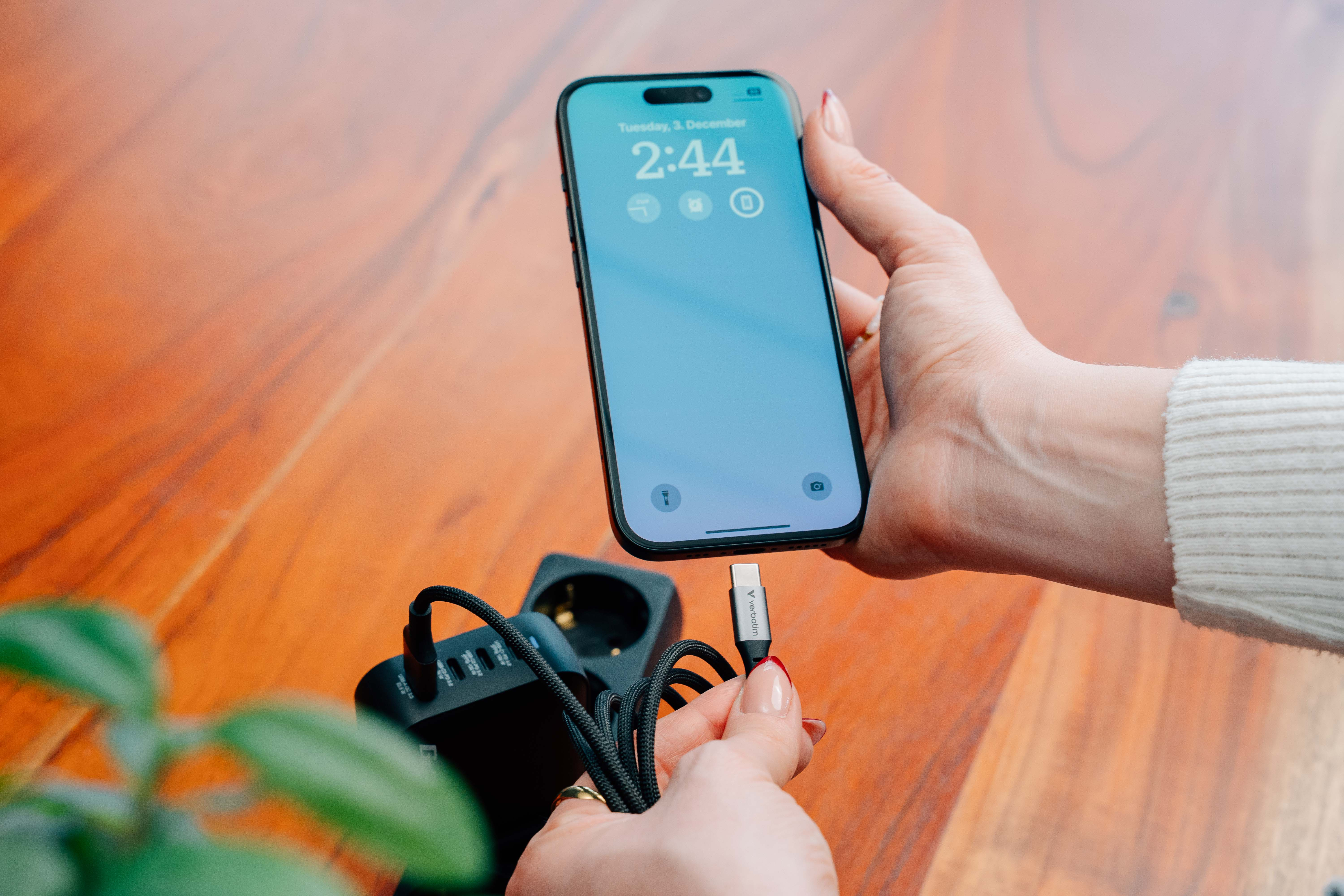 Een hand houdt een smartphone vast terwijl een USB-C-kabel wordt aangesloten.