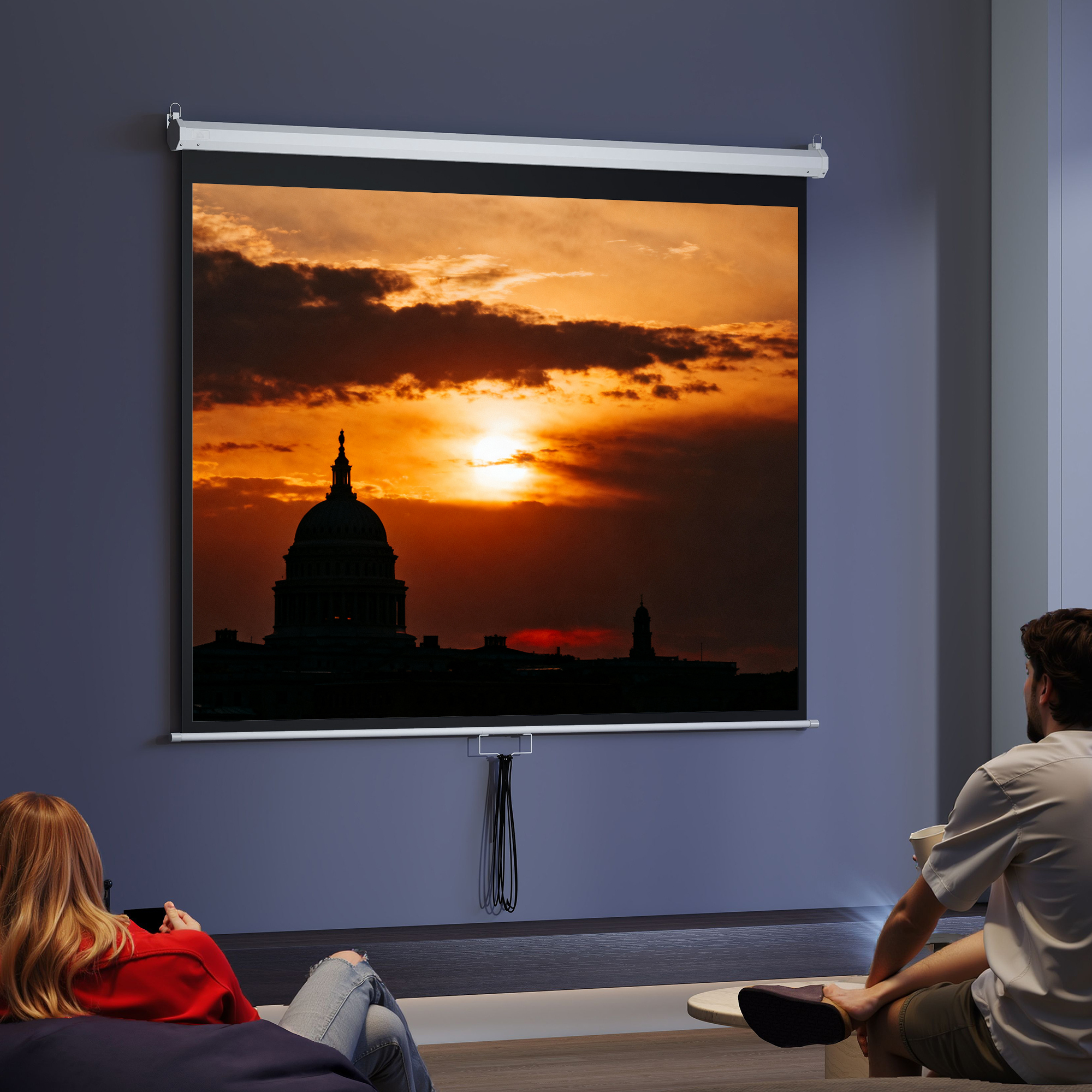 Dos personas ven una pantalla con silueta de edificio al atardecer.