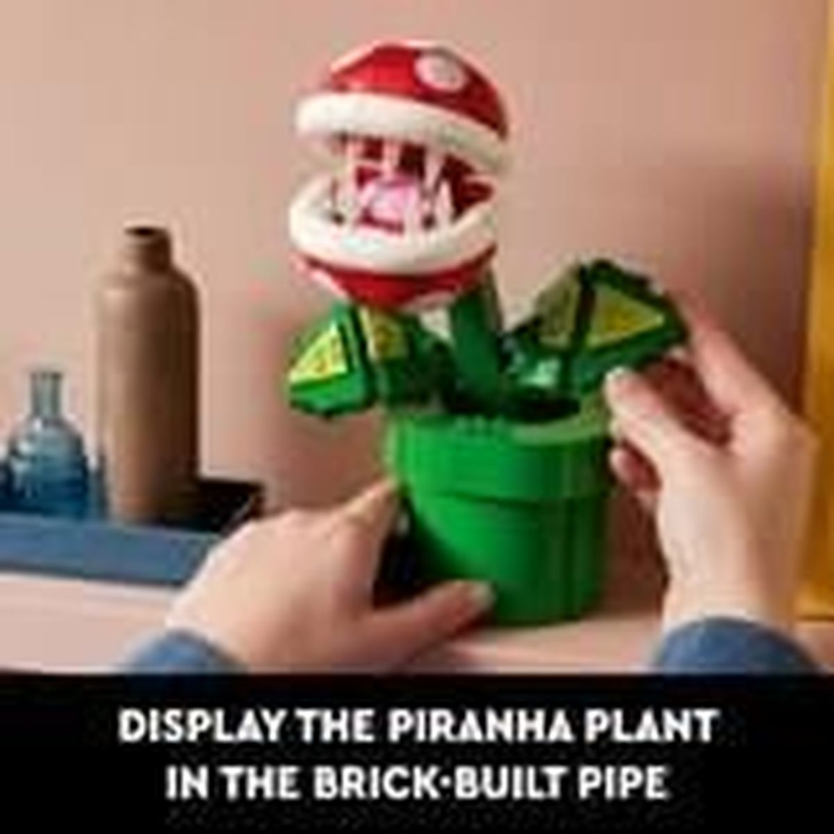 Una Pianta Piranha Lego in vaso verde. Mani stanno assemblando la pianta.