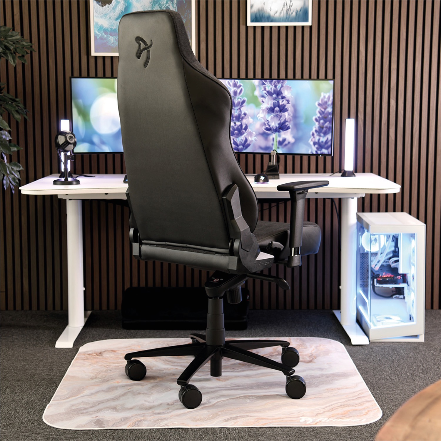 Sedia da gaming nera davanti a una scrivania con monitor e PC.