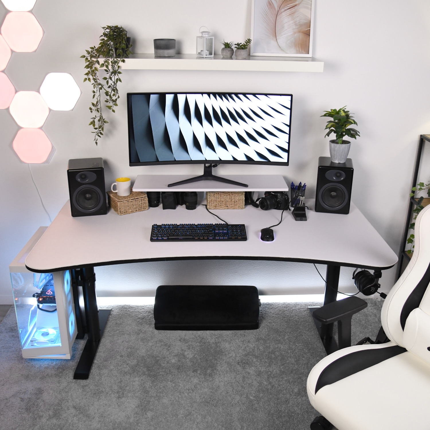 Een wit gamingbureau met monitor, toetsenbord, muis, luidsprekers en pc. Wit en zwarte stoel.