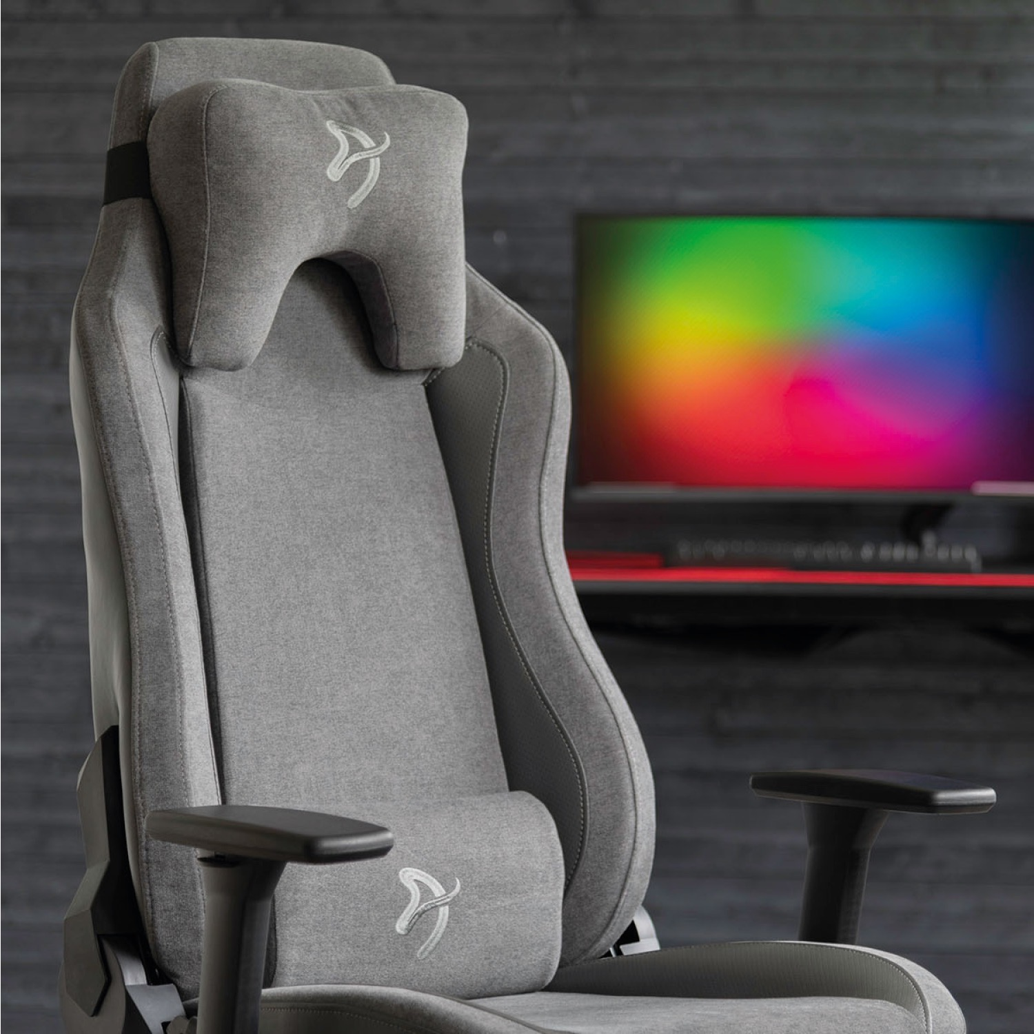 Sedia da gaming grigia con poggiatesta e cuscino lombare. Schermo con sfumatura di colori.