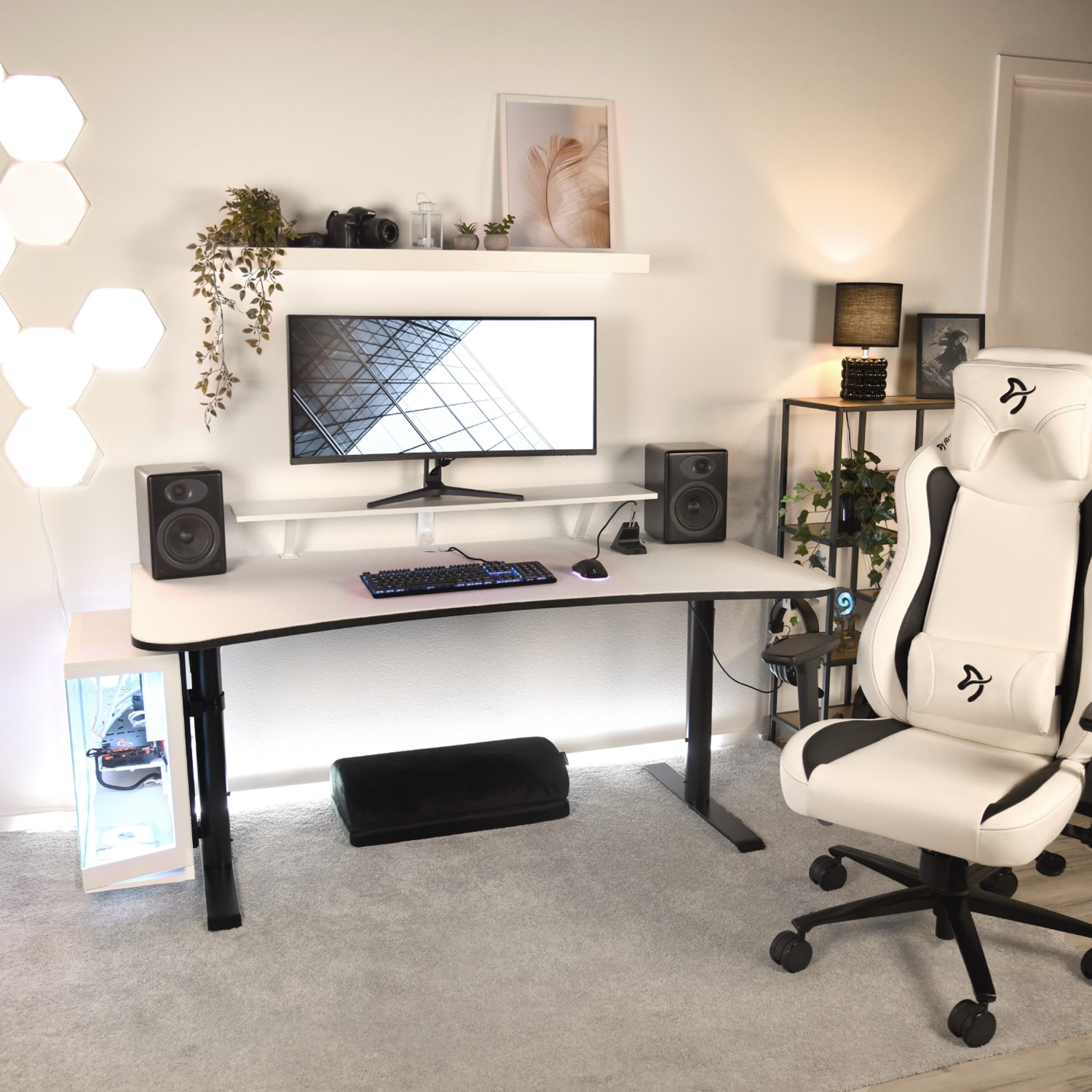 Een wit gamingbureau met monitor, toetsenbord, muis en luidsprekers. Een witte gamingstoel ernaast.