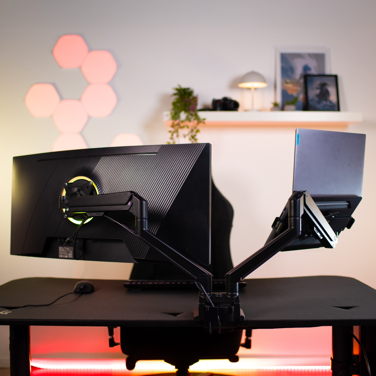 Een bureau-opstelling met dubbele monitor, laptop, muis, toetsenbord en sfeerverlichting.