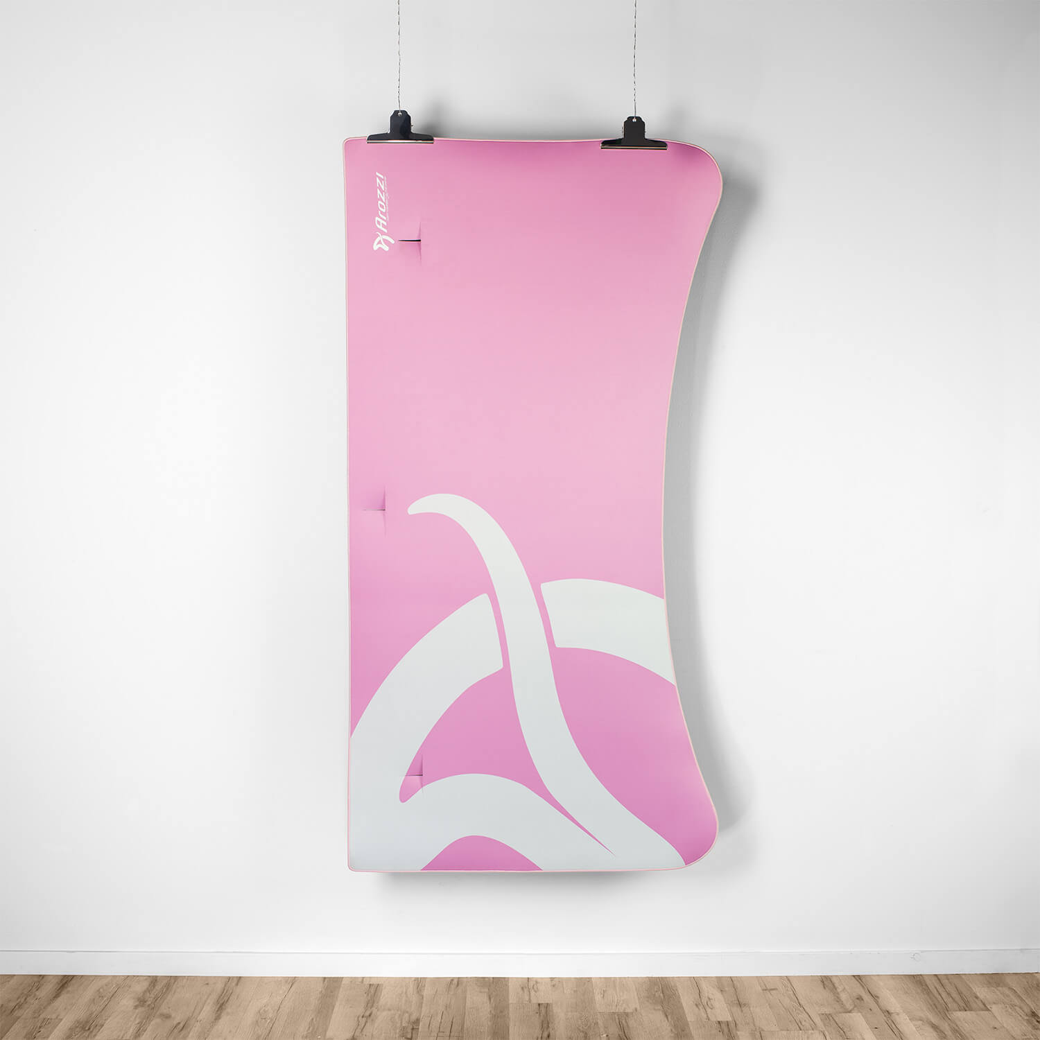 Un tappetino Arozzi rosa con disegno astratto bianco appeso a un muro bianco.