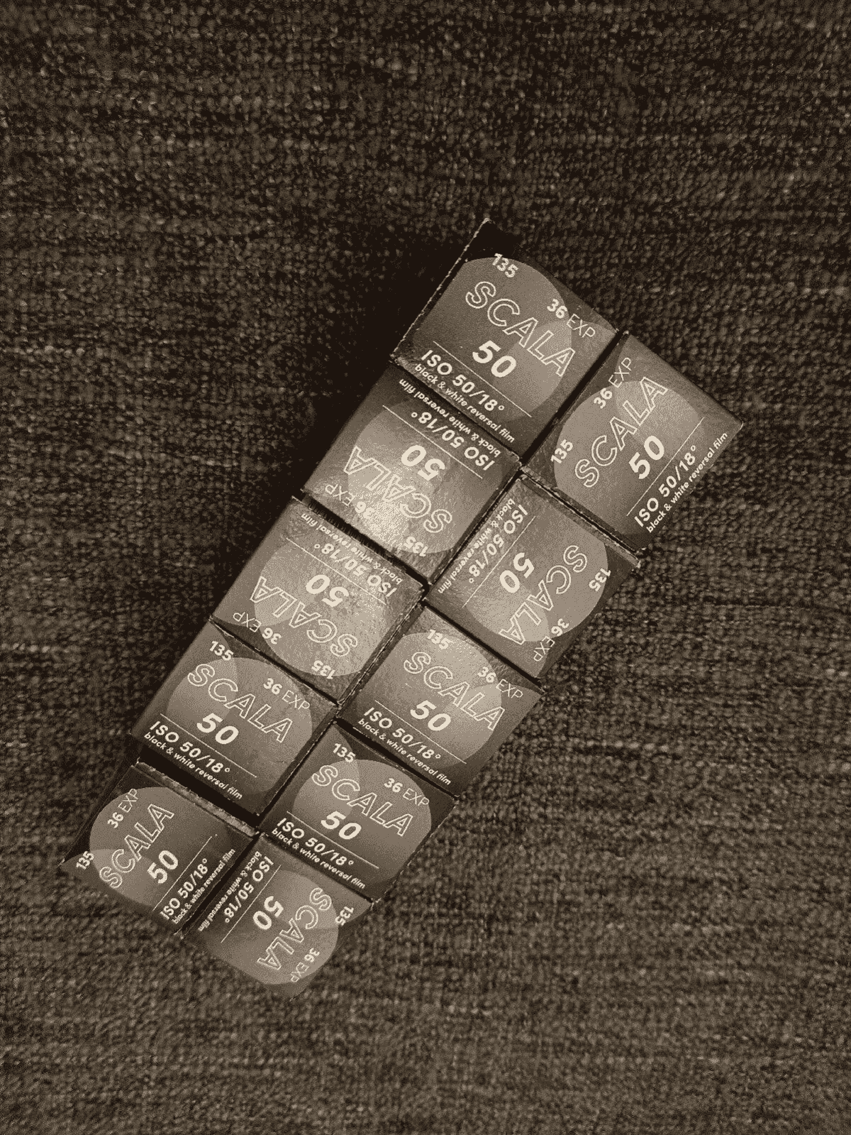 Varias cajas de película reversal blanco y negro SCALA 50 sobre una superficie oscura y texturizada.