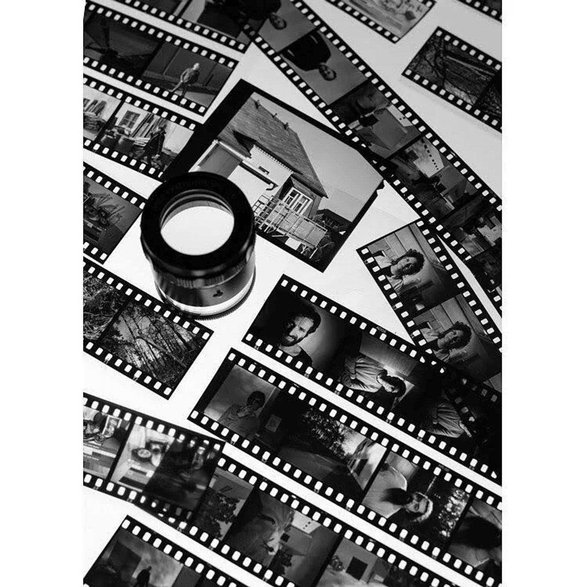 Una lupa yace sobre tiras de película con fotos en blanco y negro.