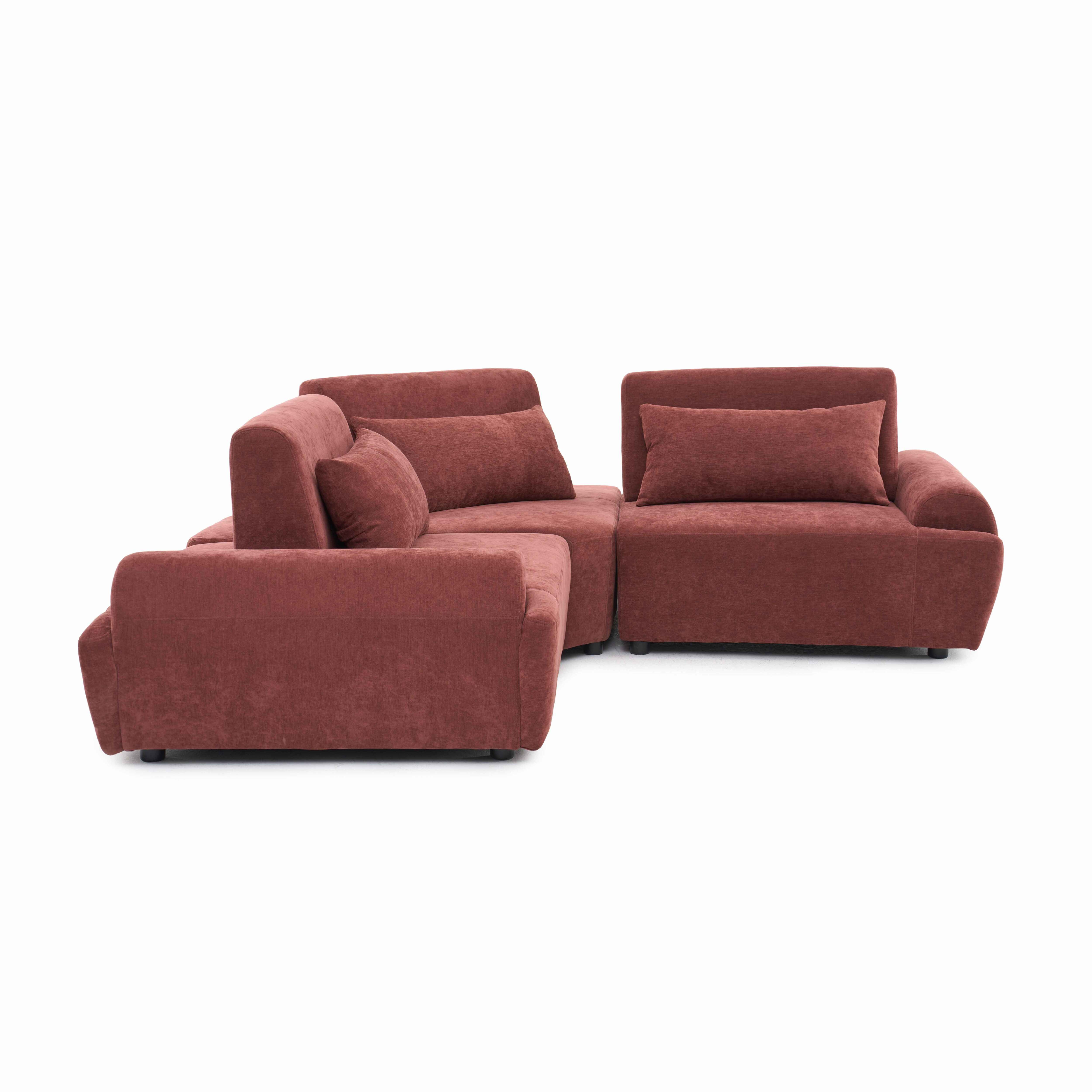 Ein korallenrotes Ecksofa mit Kissen auf weißem Hintergrund.